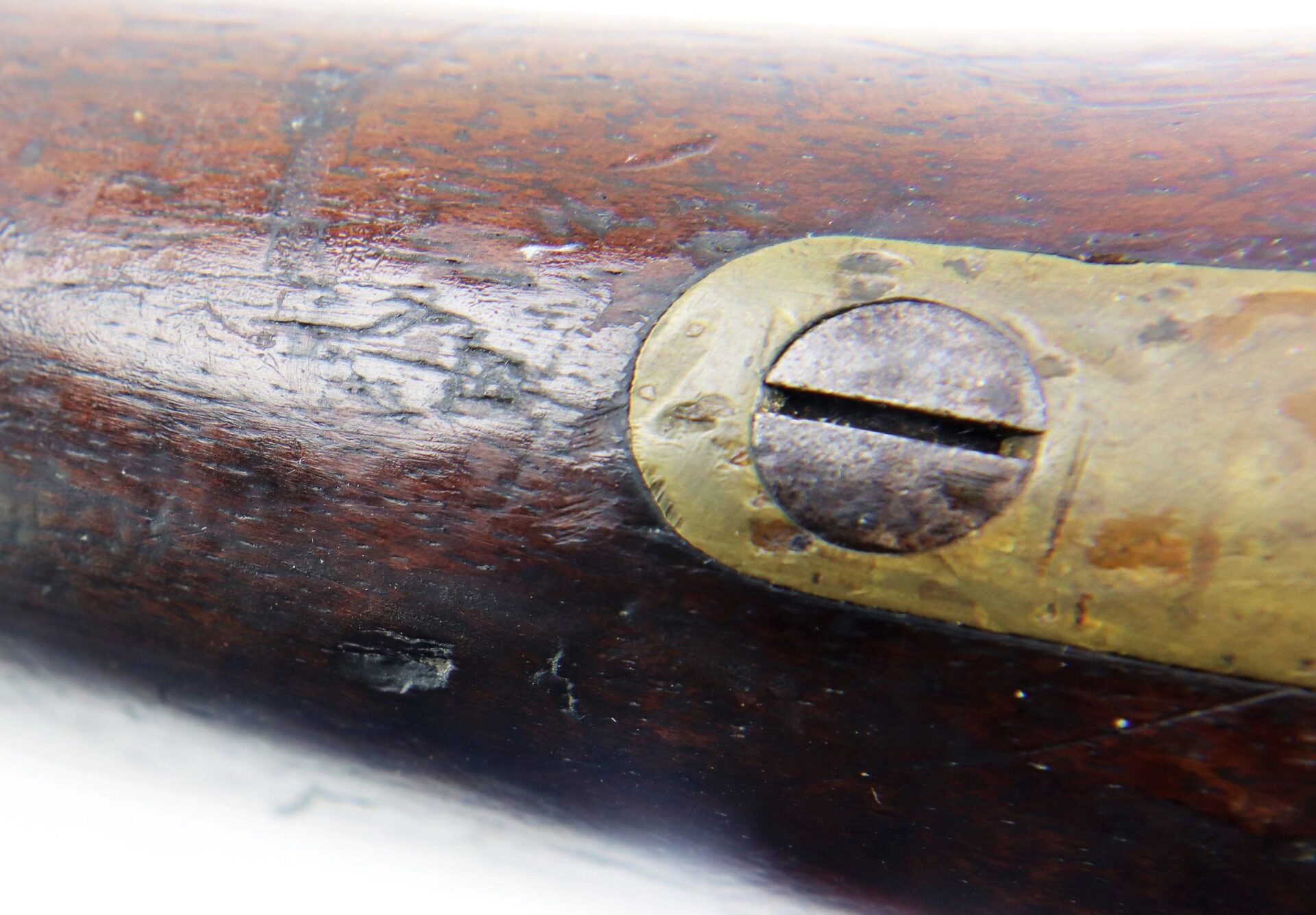 Close-up of the Confederate 1863 Dated Enfield Altered to a Cavalry Carbine, showing its old wooden surface, tarnished brass plate, and slotted screw.