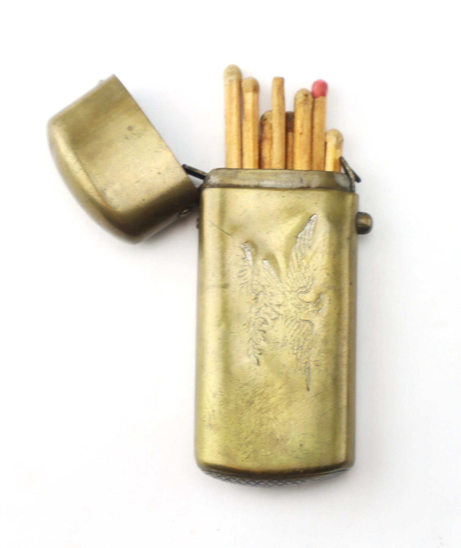 The Civil War Era Patriotic Match Safe, crafted from brass with an engraved bird design, is open to reveal several matches inside, one of which has a pink head.