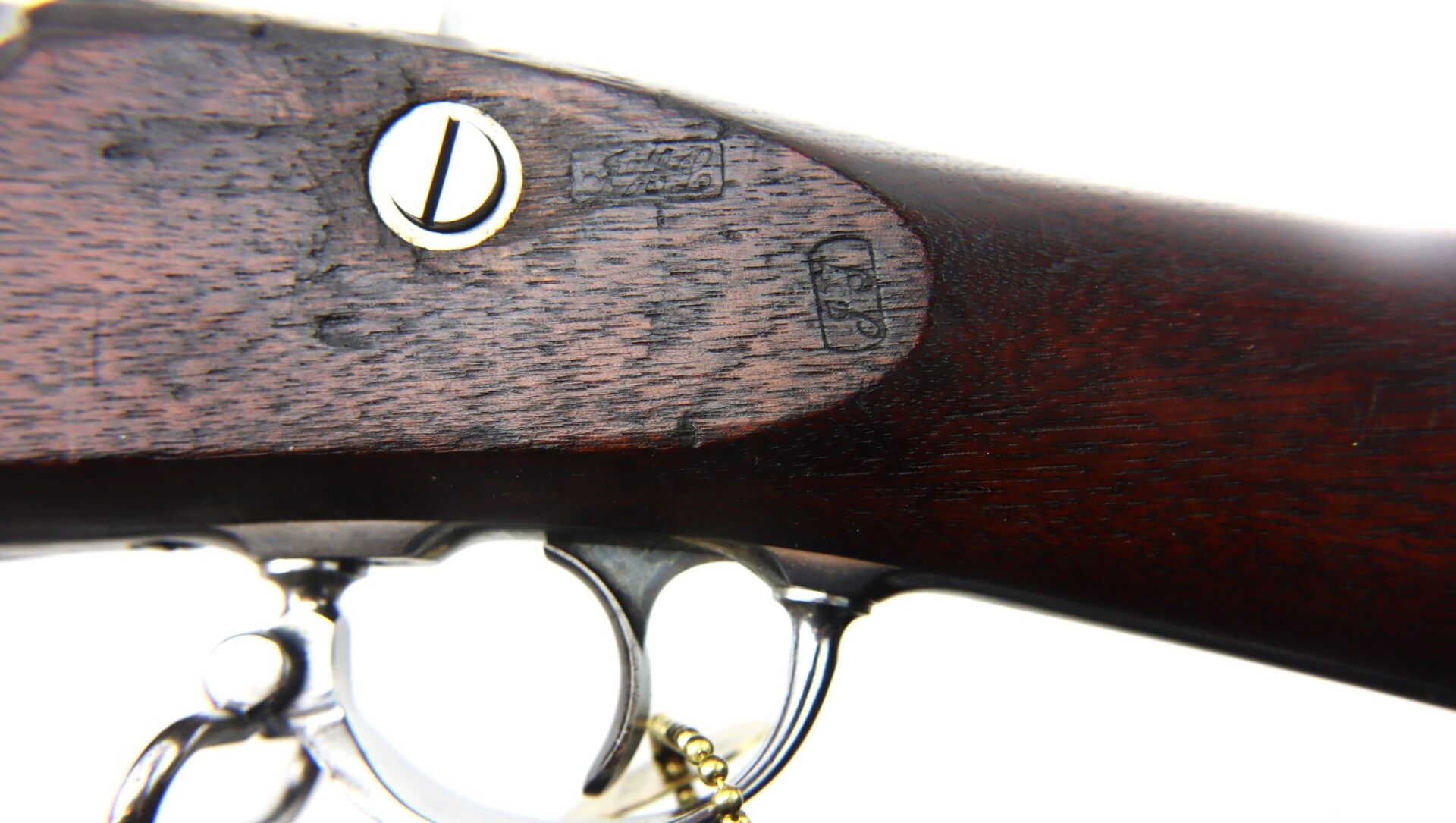Close-up of a U.S. Model 1861 Special Colt Contract Rifle Musket Dated 1864 / SLD wooden stock, highlighting a screw, stamped markings, and part of the metal trigger guard against a white background.