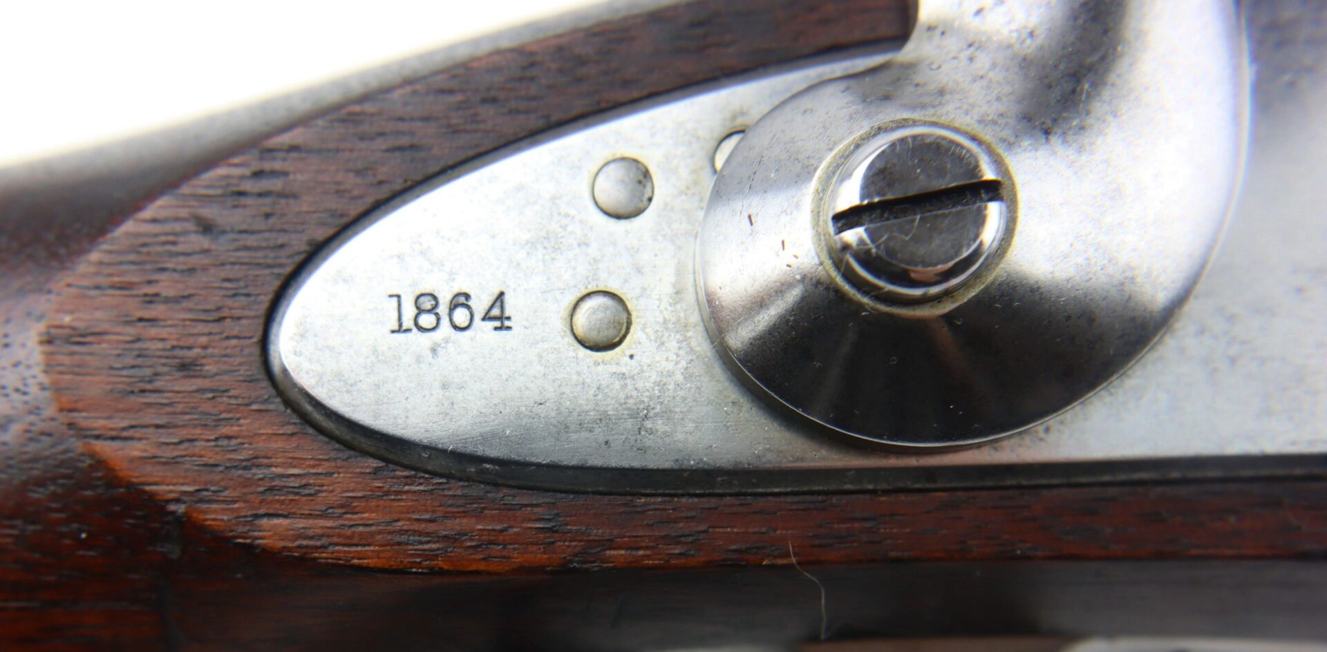 Close-up of a metal plate on the wooden stock of a U.S. Model 1861 Special Colt Contract Rifle Musket, engraved with "1864" near a screw.