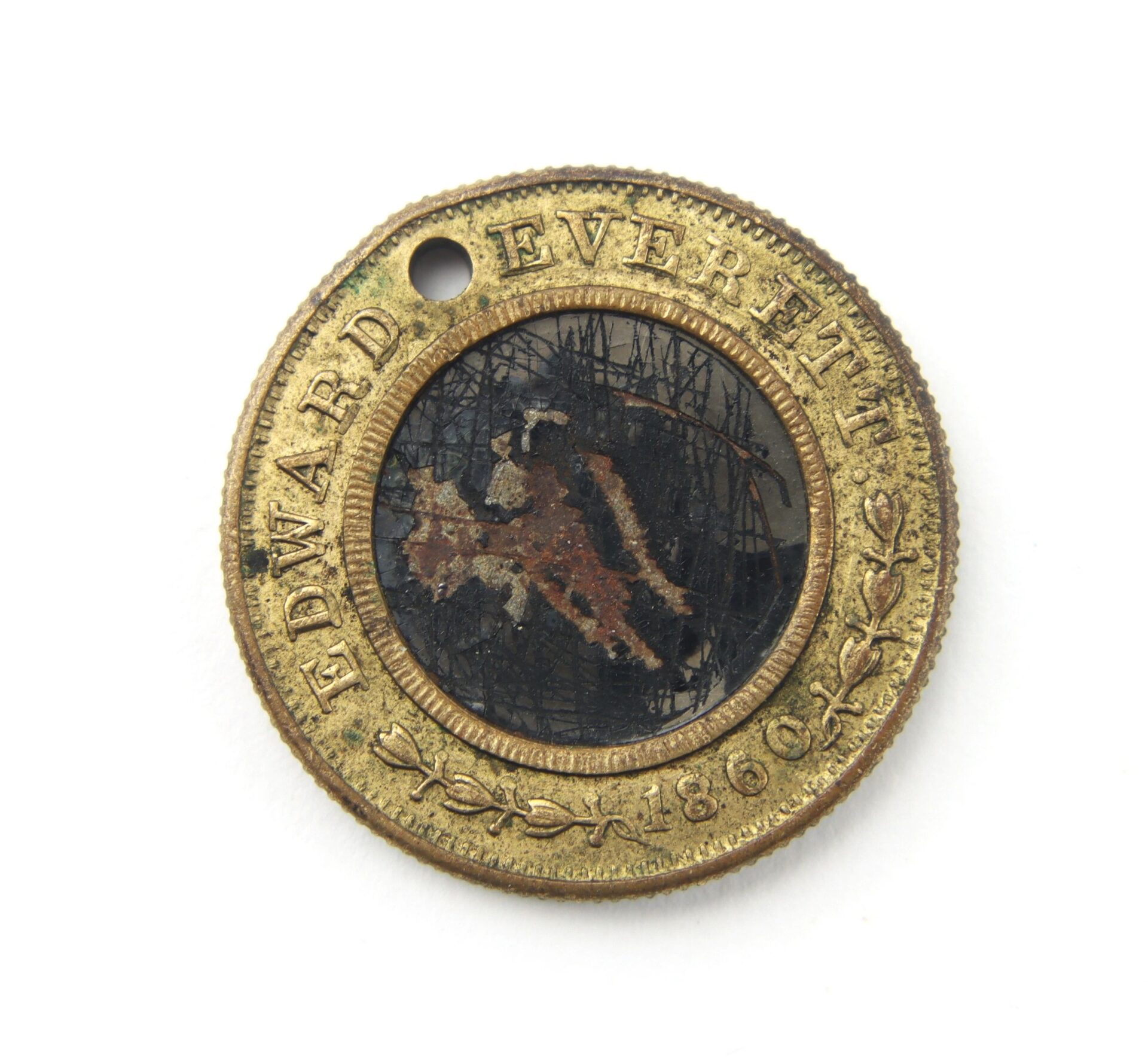 A round brass Bell / Everett Campaign Token from 1860, inscribed "EDWARD EVERETT" around the edge, has a small hole near the rim and a faded central image.