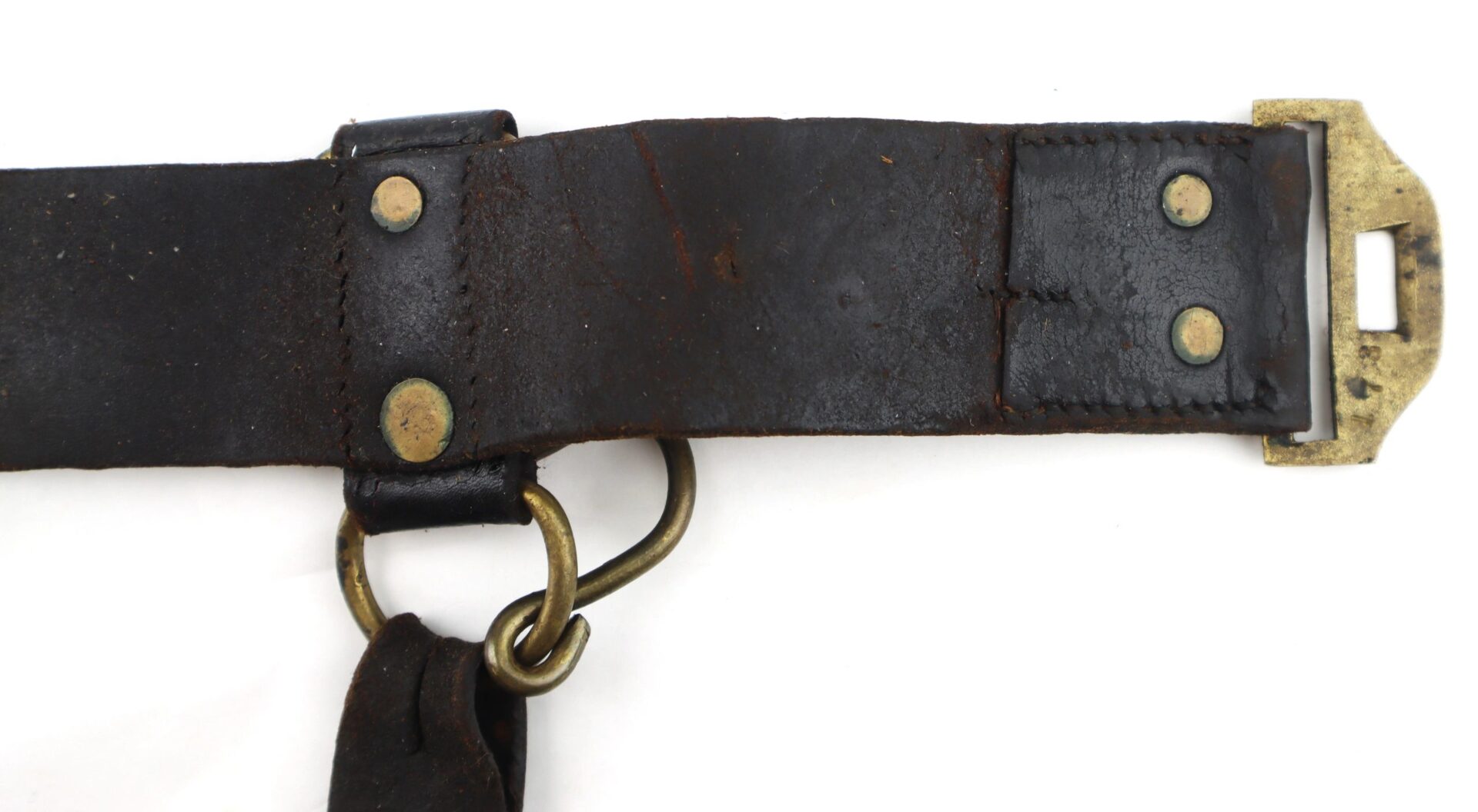 Close-up of a Model 1851 Saber Belt, featuring worn black leather, brass rivets, a rectangular buckle, and an attached metal ring.