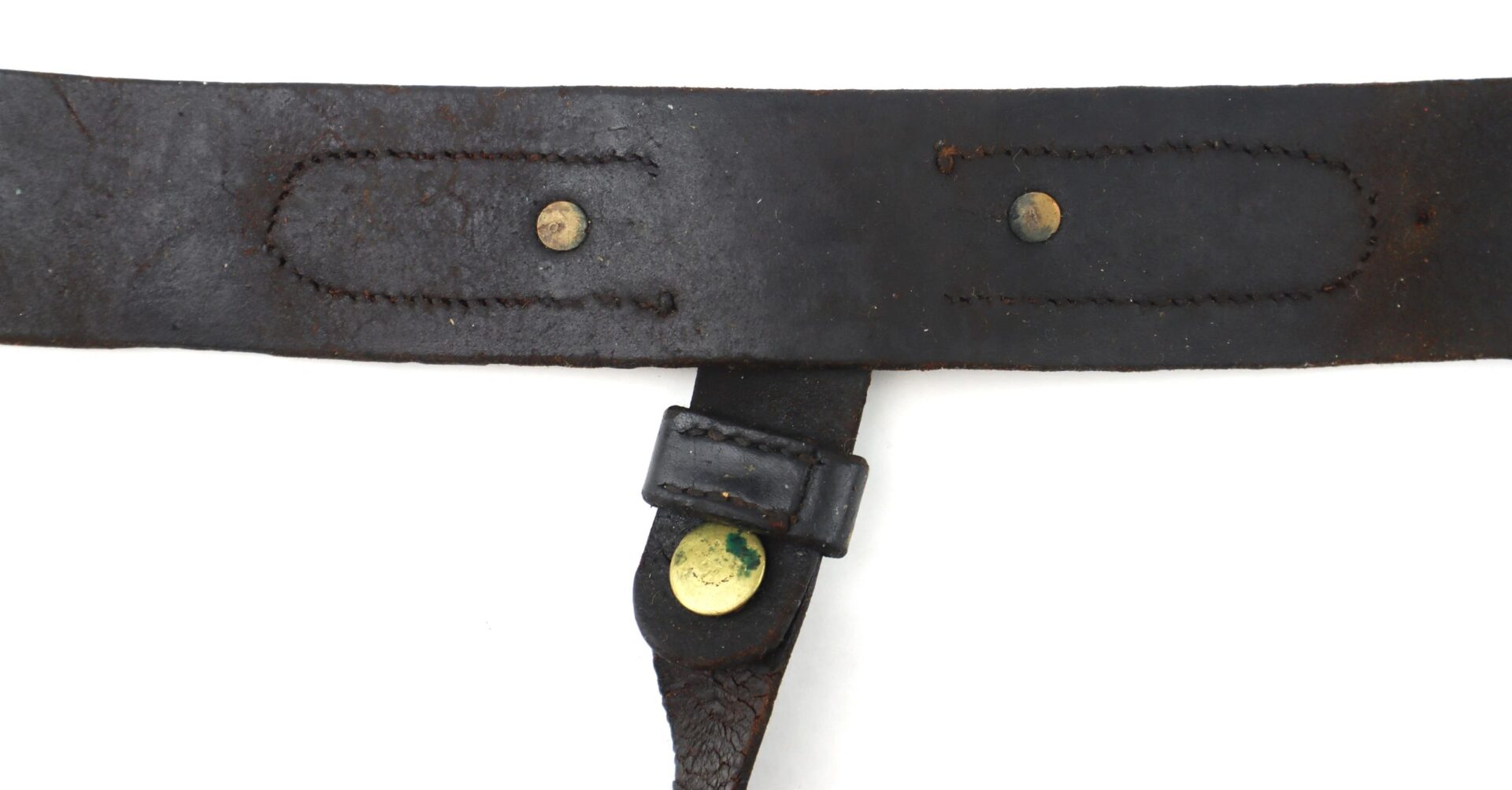 Close-up of the Model 1851 Saber Belt’s worn, dark leather strap featuring two rivets and a smaller attached leather piece secured by a brass fastener.