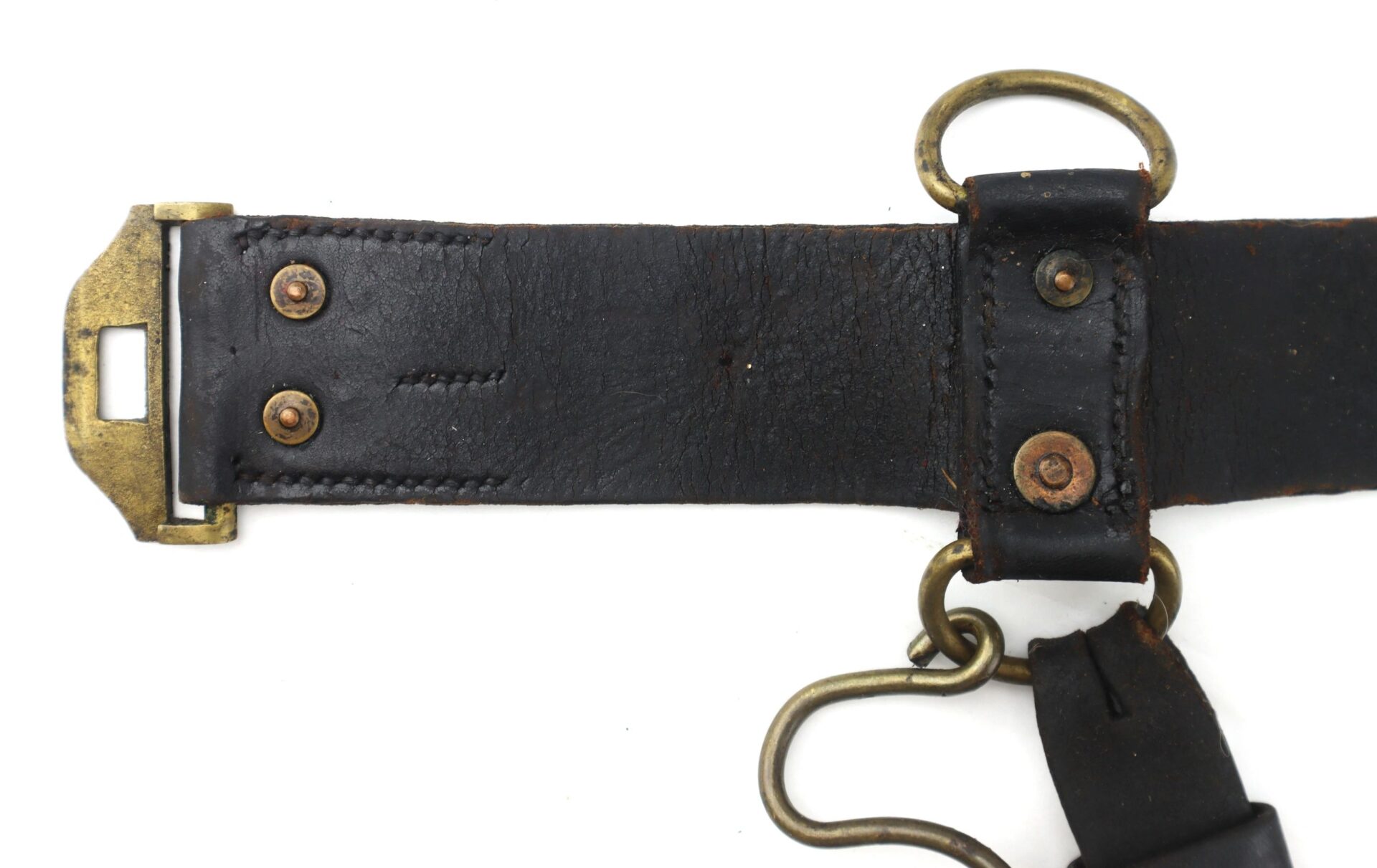 A close-up of the Model 1851 Saber Belt, featuring a black leather strap with brass hardware: a rectangular buckle, rivets, and a metal ring for attachment.