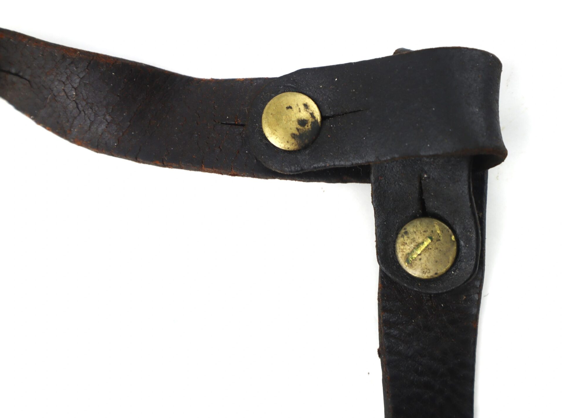 Close-up of two intersecting black leather straps from the Model 1851 Saber Belt, secured with brass rivets against a white background.