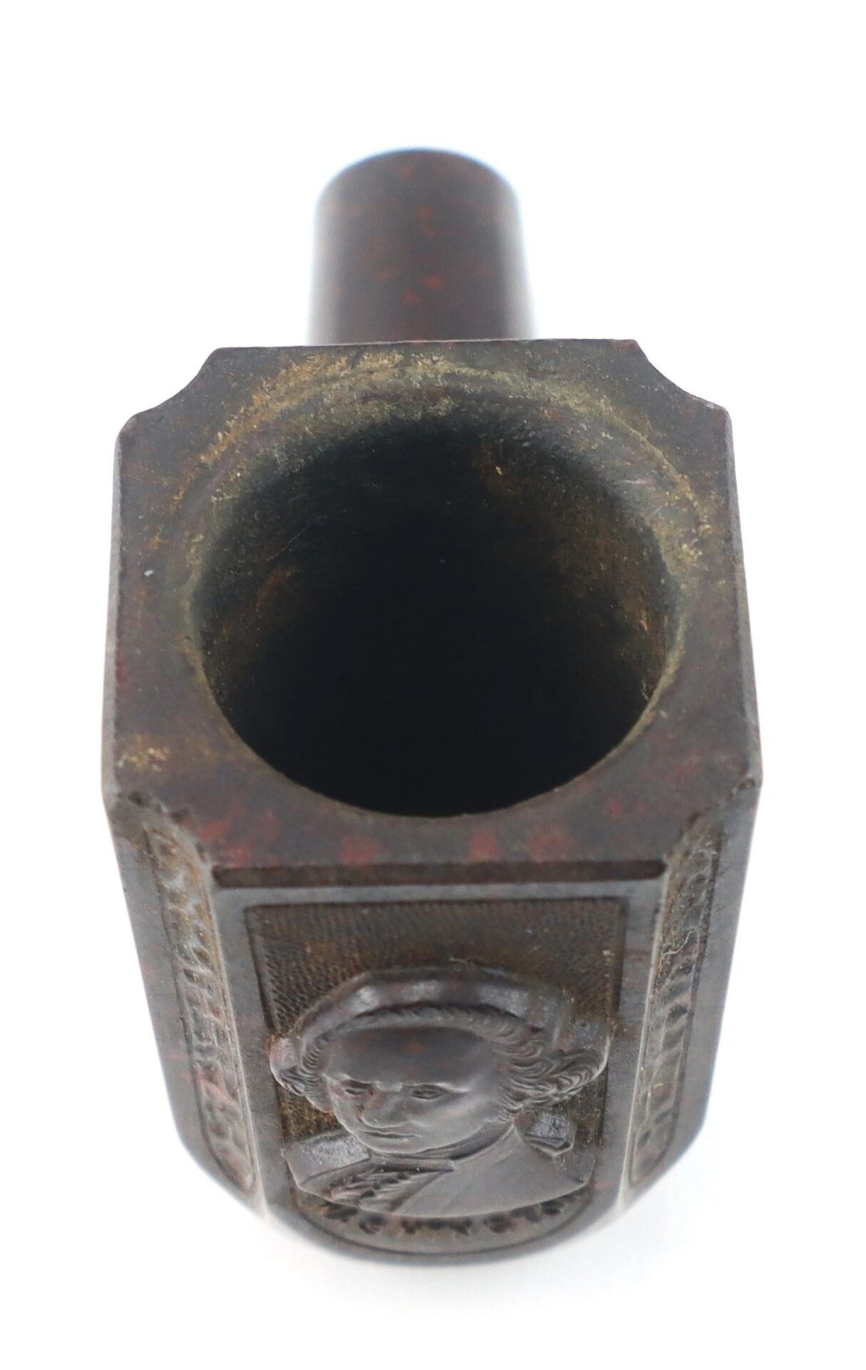 A close-up view of the General George Washington Gutta-Percha Pipe from circa 1850, featuring a carved portrait on its dark-colored bowl.