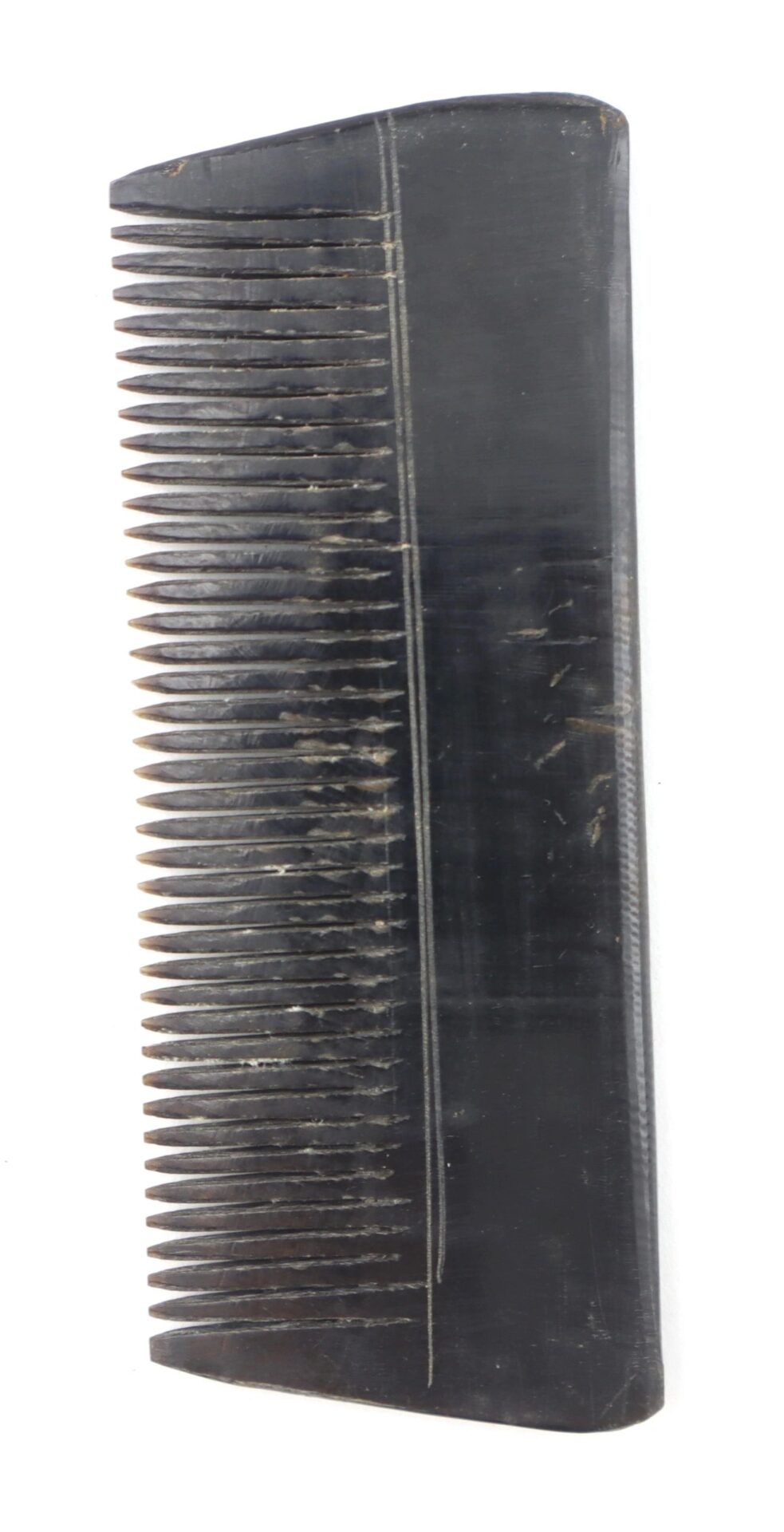 A Civil War-era comb made of horn, featuring fine and wide teeth, displayed against a white background. / SOLD.