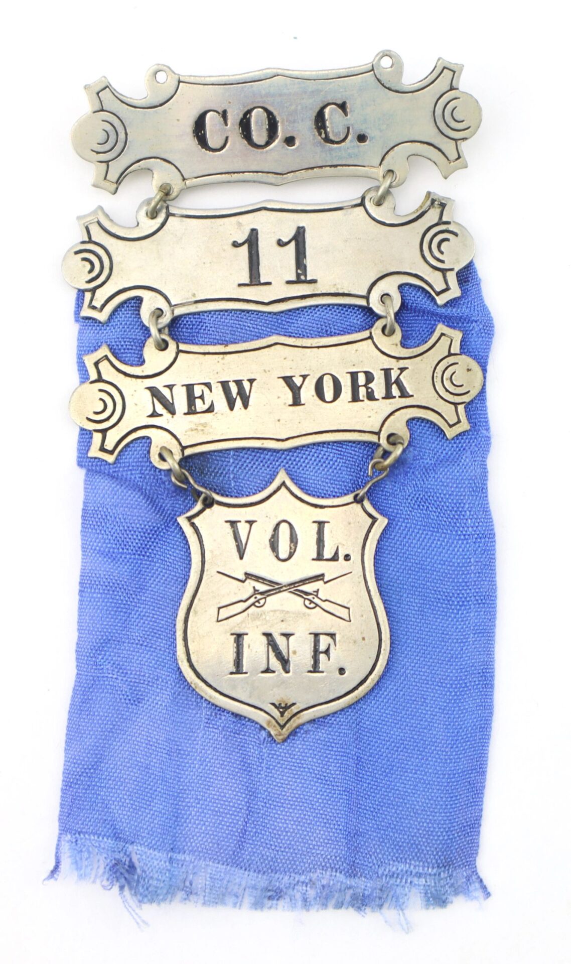 Four brass badges on blue fabric read: "C.O.C.", "11", "NEW YORK", and "VOL. INF." with crossed rifles—this ladder badge belonged to the 11th New York Infantry, “Ellsworth Zouaves.” / SOLD.