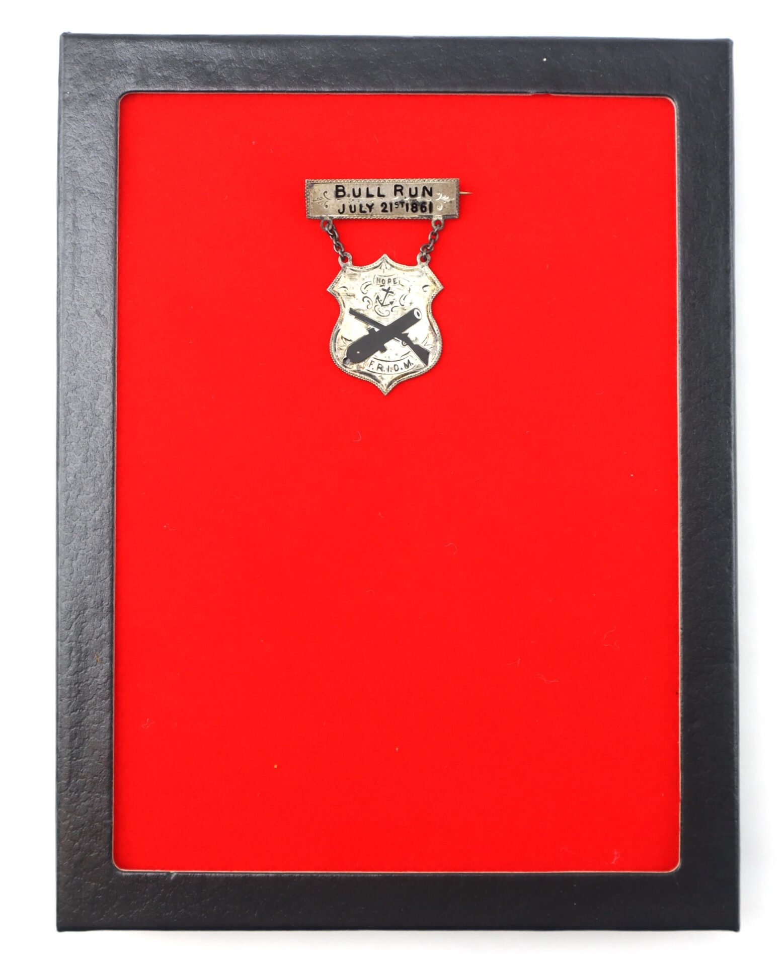 A framed Rhode Island Regimental Badge “Bull Run July 21 1861” (F.R.I.D.M - First Rhode Island Detached Militia) with pin displayed against a red background.