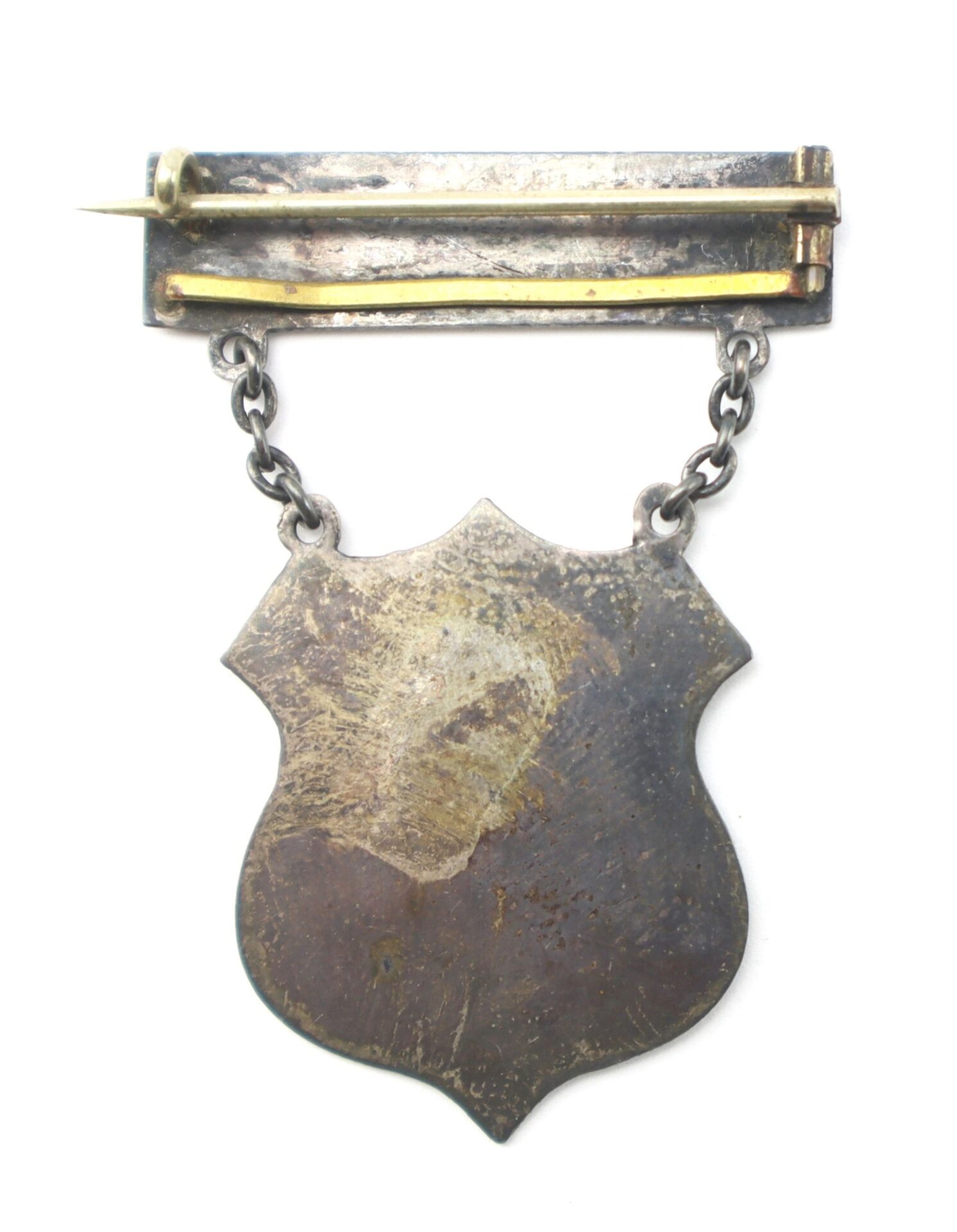 A Rhode Island Regimental Badge “Bull Run July 21 1861” F.R.I.D.M - First Rhode Island Detached Militia hangs from a short chain attached to a rectangular pin bar, featuring a shield shape and metallic finish.