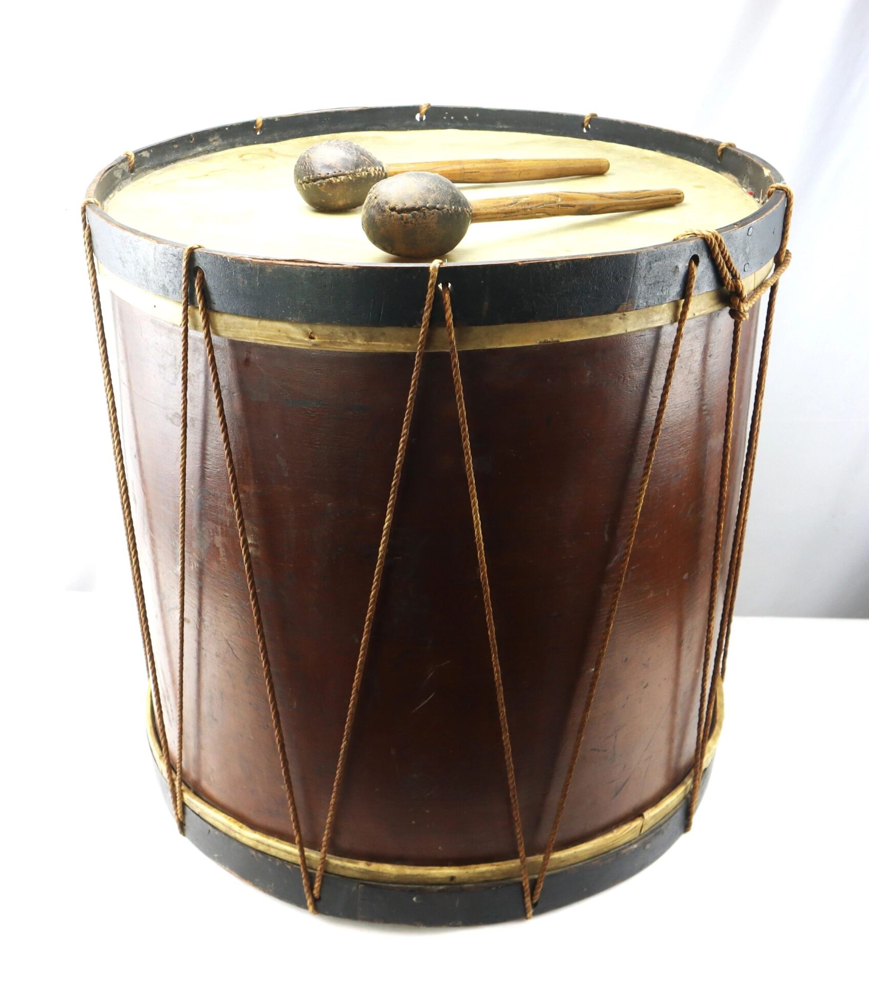 The “Galvanized Yankees” Regimental Bass Drum of the 1st U.S. Volunteers is a large, cylindrical wooden drum with rope tensioning and two drumsticks resting on top.