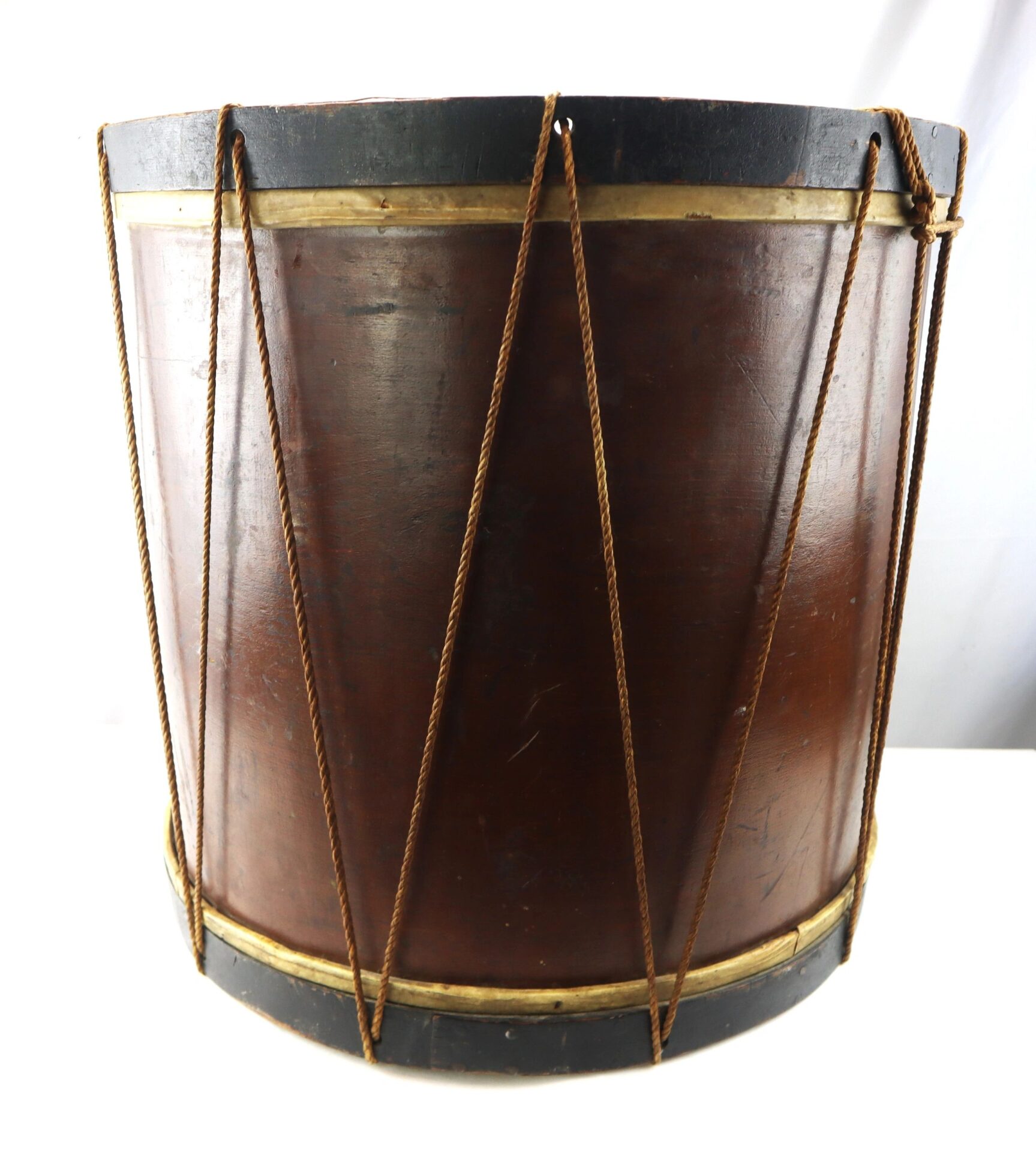 The “Galvanized Yankees” Regimental Bass Drum of the 1st U.S. Volunteers is a large, cylindrical wooden drum featuring a dark brown body, black rims, and rope tensioning along the sides.
