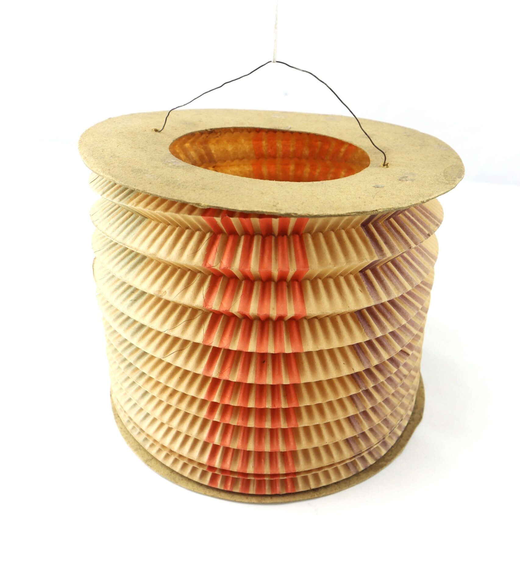 The Political Parade Lantern is a vintage paper lantern with a ribbed, accordion-style body, thin wire handle, and red and purple vertical stripes.