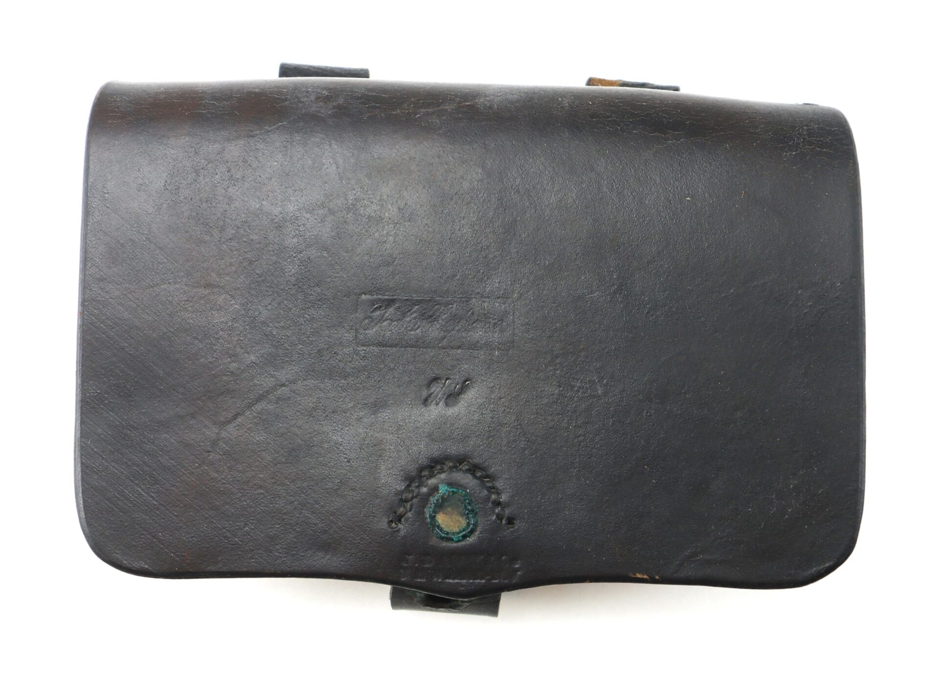 A worn black leather Pistol Cartridge Box with a flap closure, visible stitching, and a circular greenish stain near the bottom center.