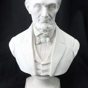 White plaster bust of Abraham Lincoln, featuring a beard and bow tie in a suit, displayed against a black background.