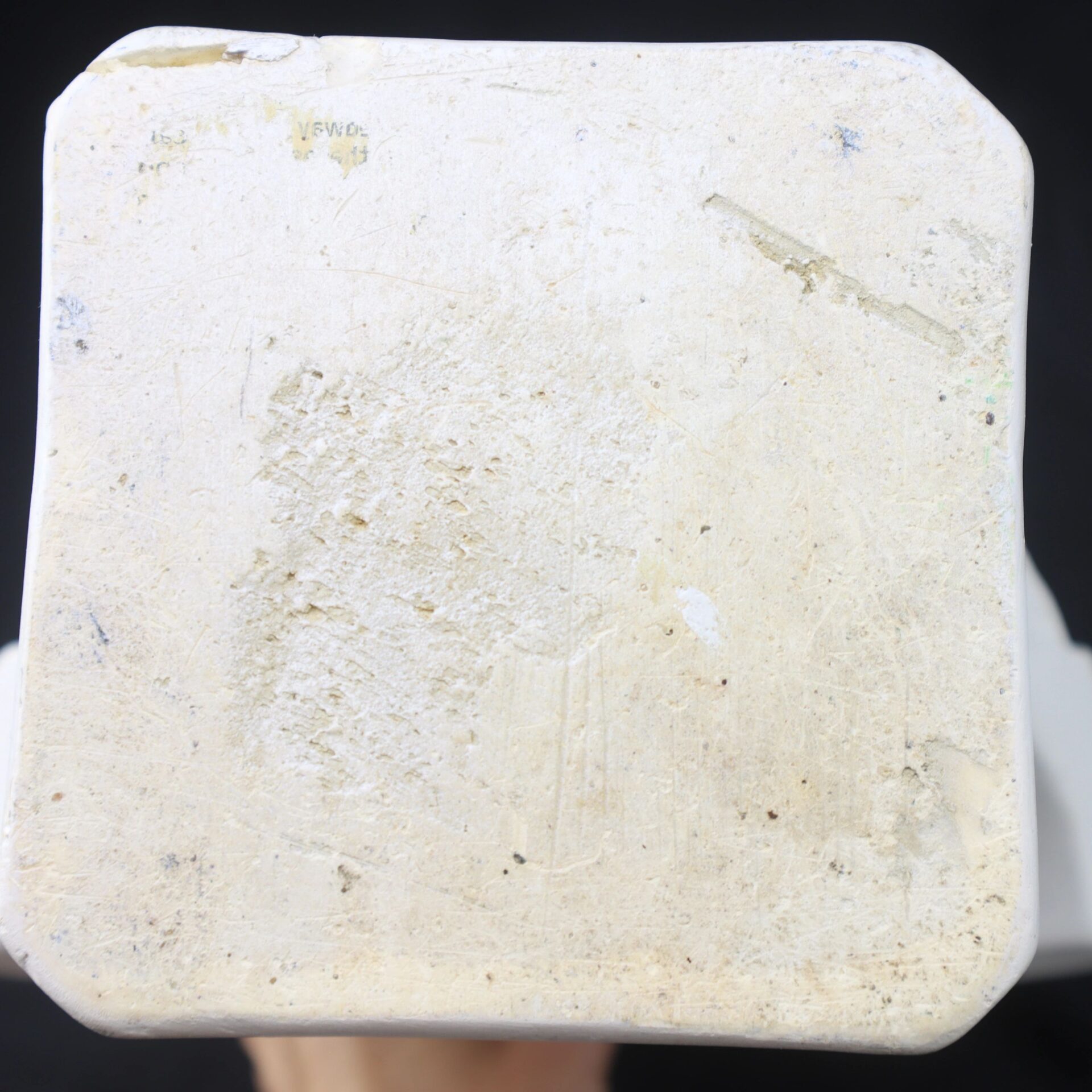 Close-up view of the base of the Abraham Lincoln ceramic object, white in color and showing visible scratches, scuffs, and minor discoloration.