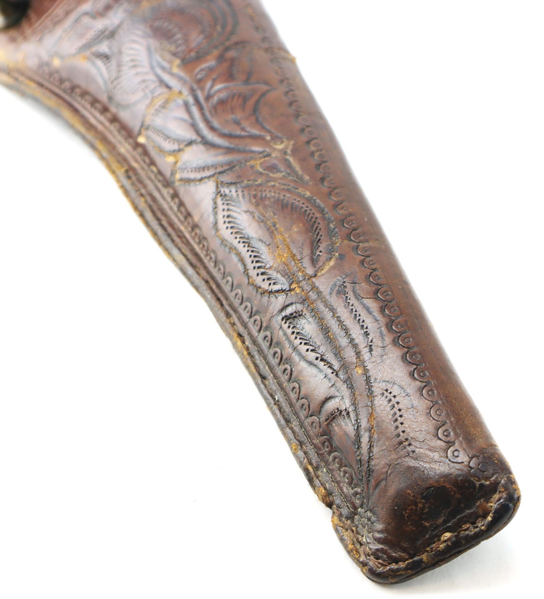 Close-up of the Wonderful “Rose of Texas” Holster, a worn brown leather holster featuring decorative stitching and floral embossing, displayed on a white background.