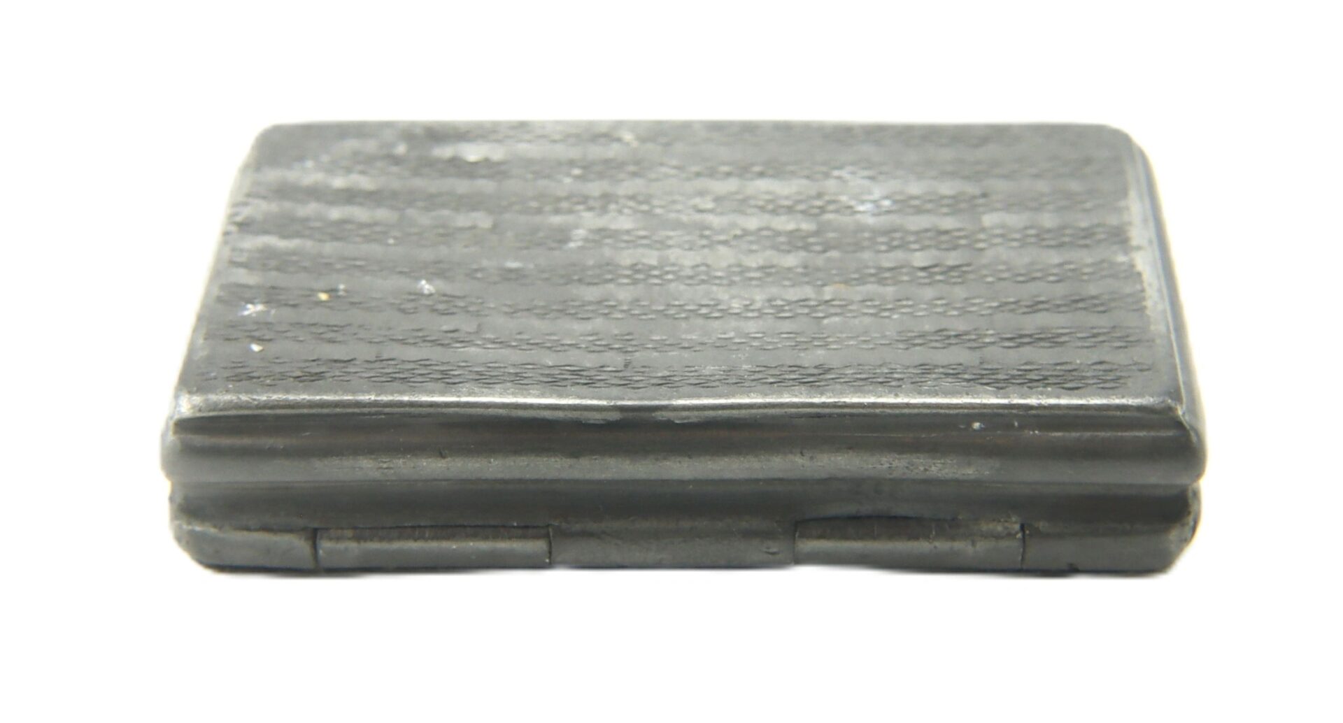 A Civil War Snuff Box, rectangular with a textured, dark grey surface and slight elevation, viewed from the side on a white background.