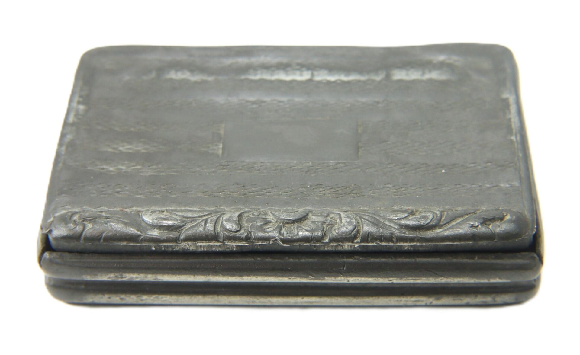 Rectangular, dark-colored Civil War snuff box with intricate metal patterns, a hinged side, and engraved floral details on the front edge. / SOLD.
