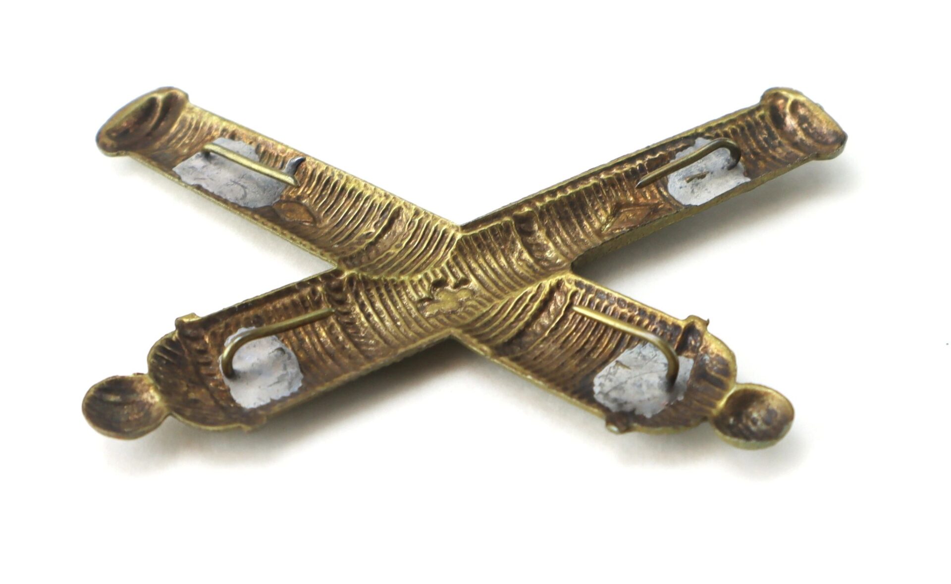 Officer’s False Embroidered Artillery Insignia with worn brass crossed cannons, tarnished areas, and visible silver solder marks displayed on a white background. Item marked as SOLD.
