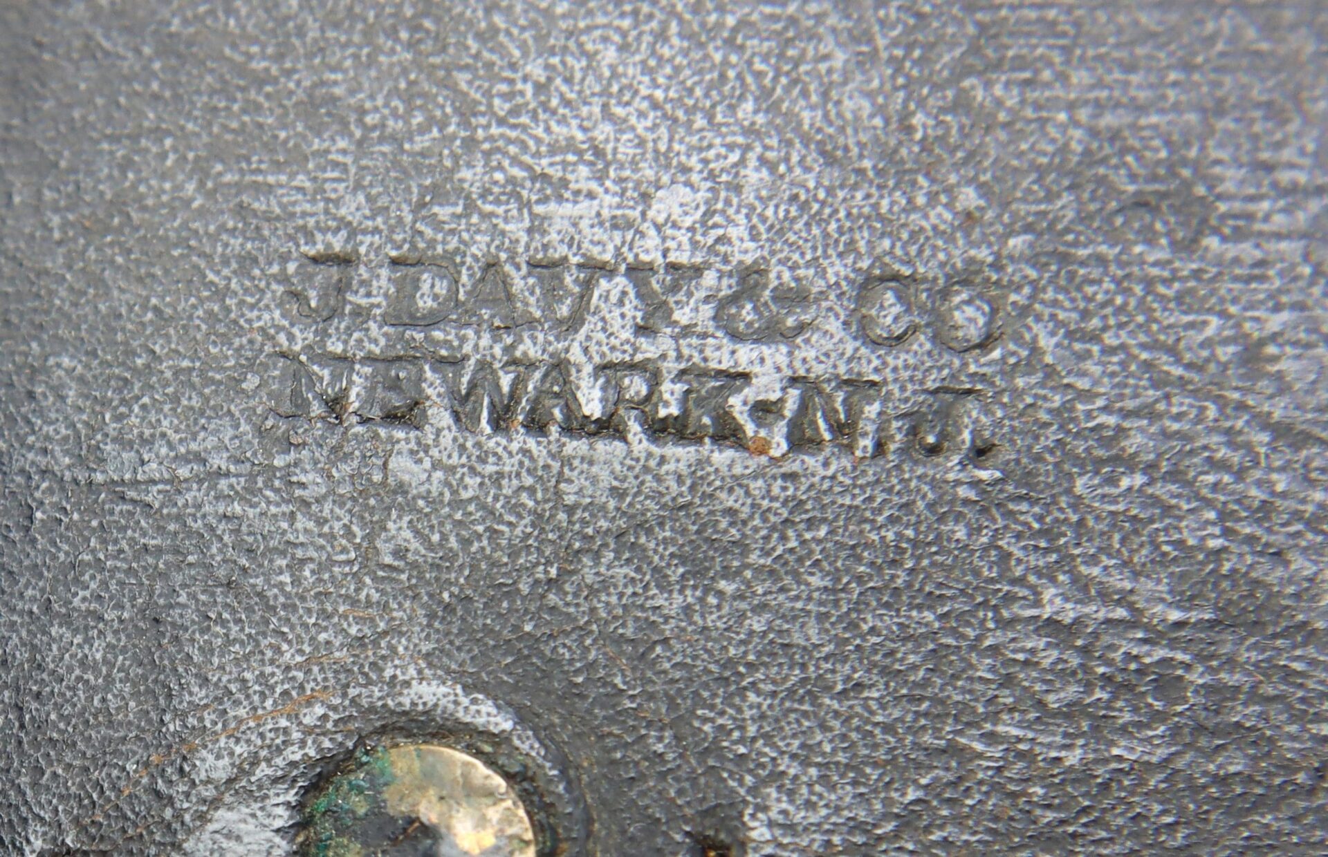 Close-up of a Civil War Pistol Cartridge Box, marked "J. Davy & Co.", showing stamped metal near a corroded bolt or rivet.