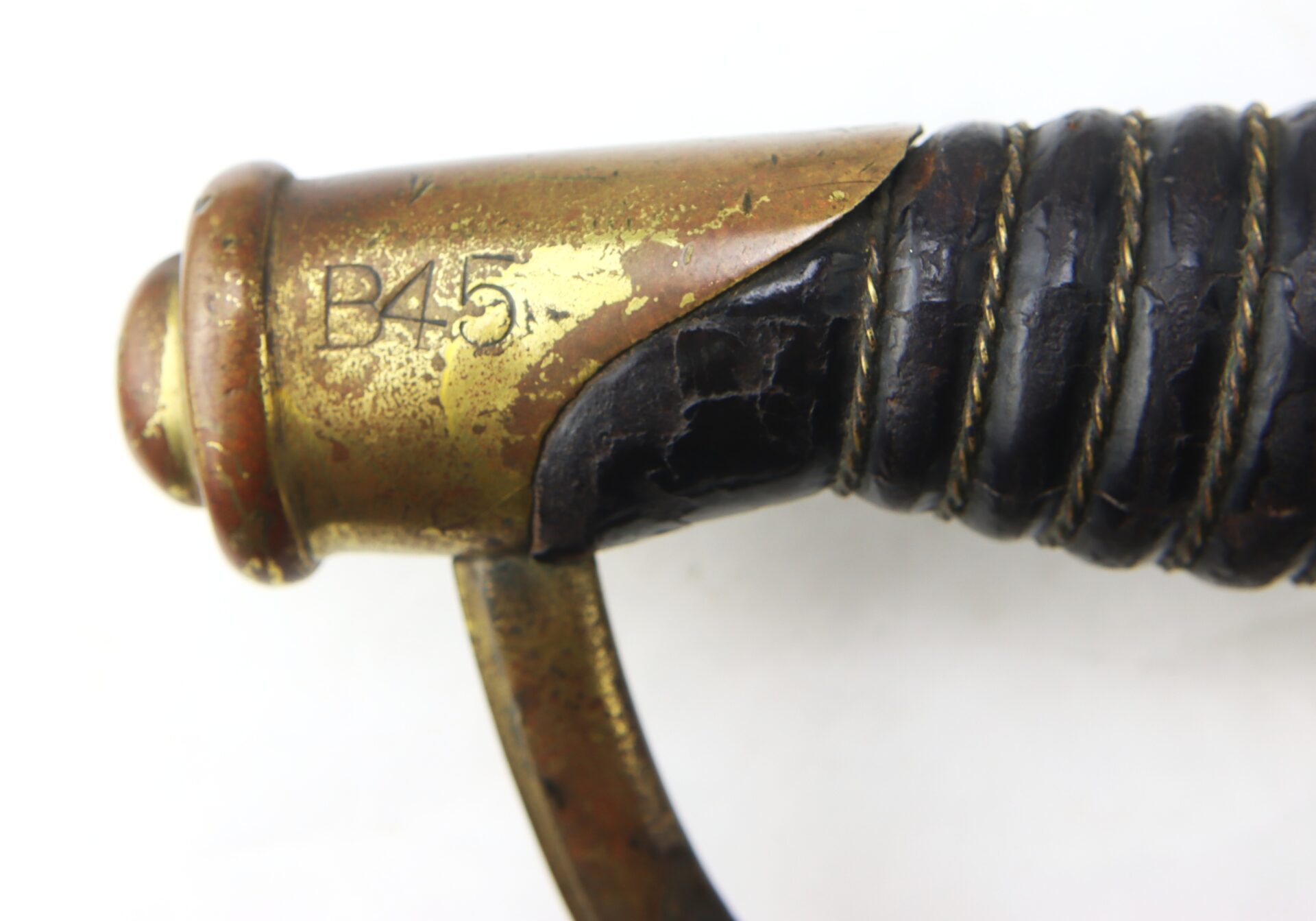 Close-up of a brass sword hilt with the marking "B45" engraved, showing worn black leather wrapping and visible aging.