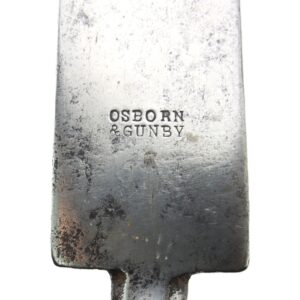 Close-up of a metal object stamped with the words "OSBORN & GUNBY"; surface shows signs of tarnish and wear.