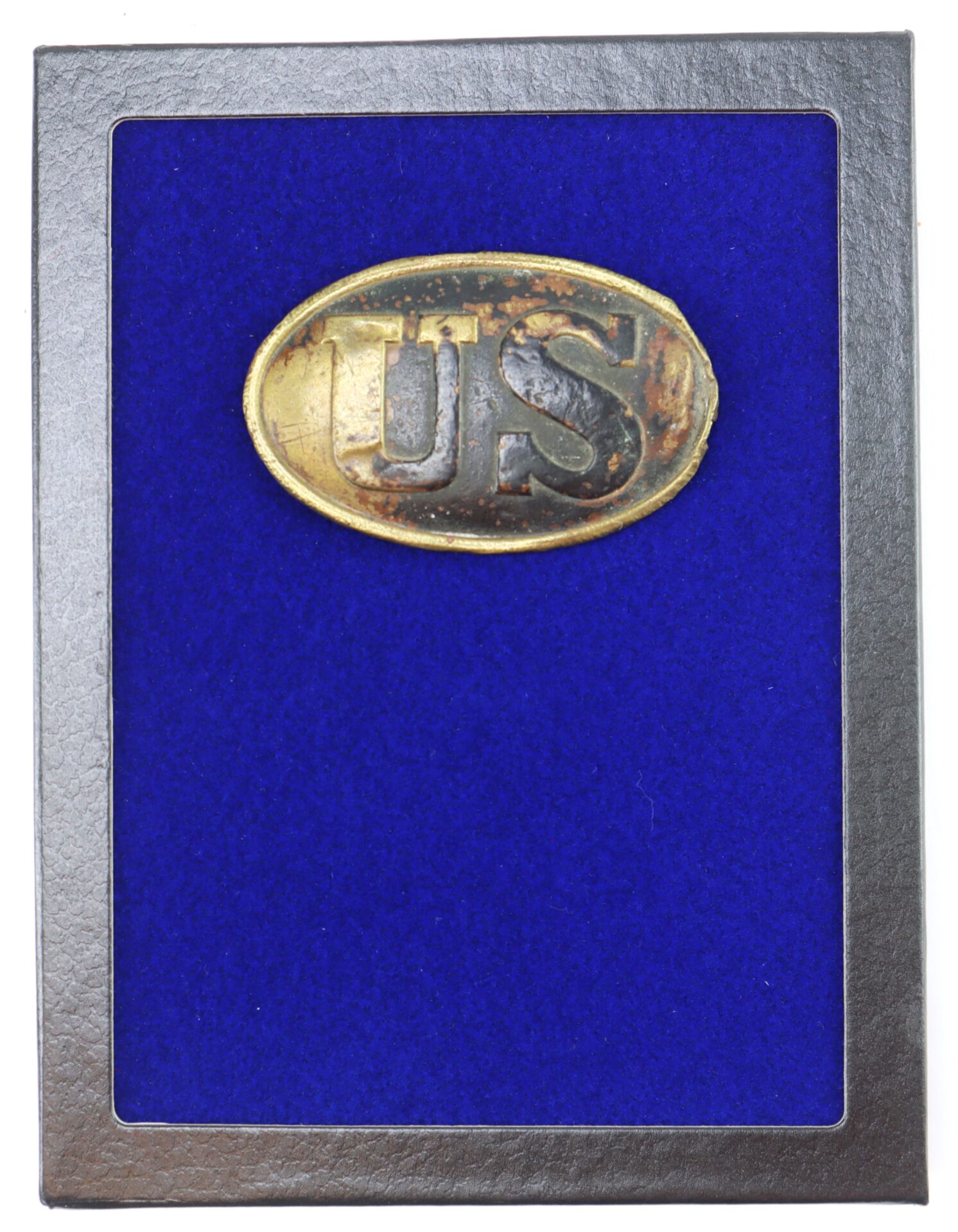 A Civil War U.S. Cartridge Box Plate with raised "US" lettering in brass is showcased on a blue velvet background within a rectangular frame.