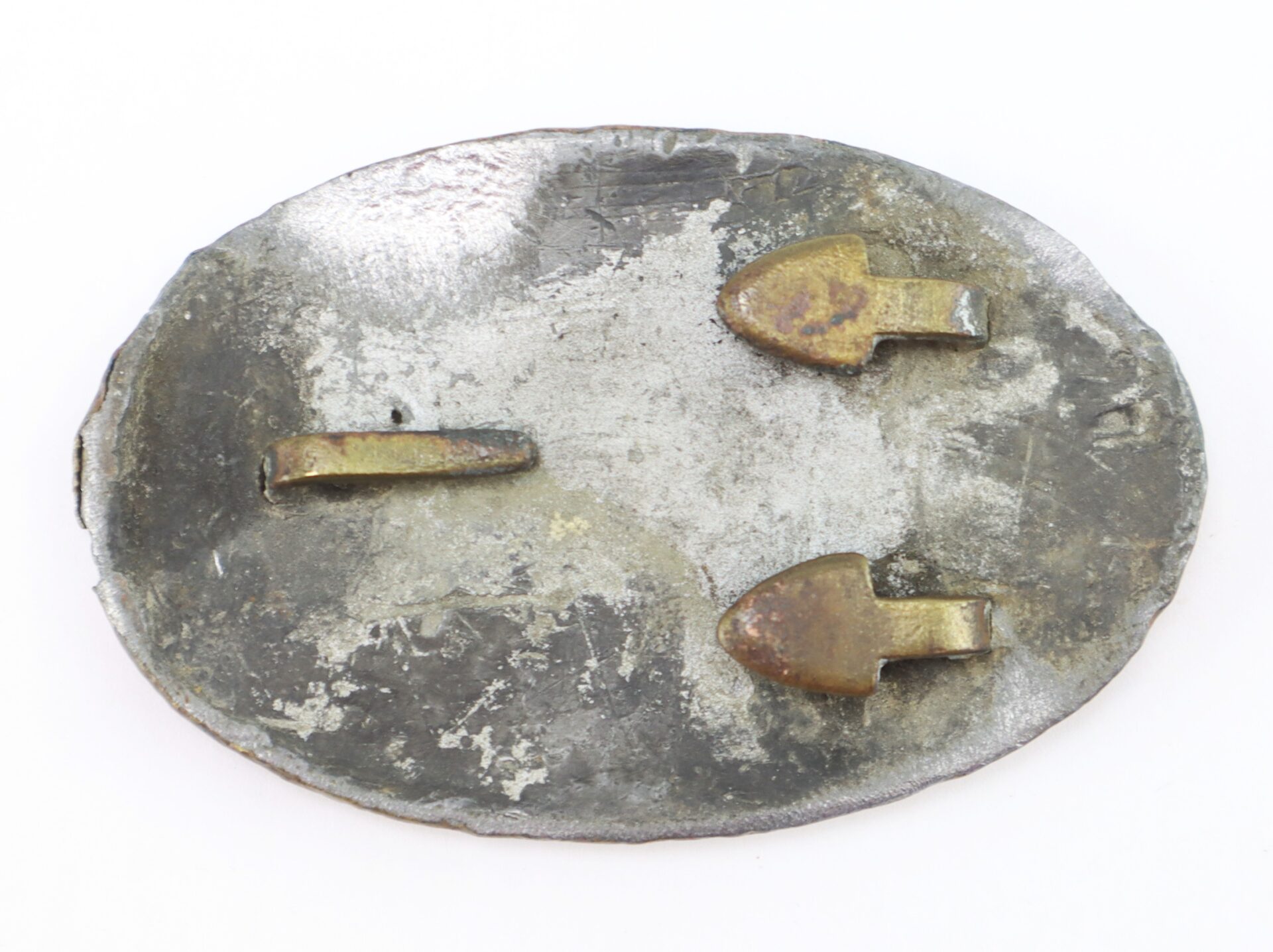 A tarnished, oval Civil War U.S. Cartridge Box Plate with three brass prongs on one side, displayed against a plain white background.