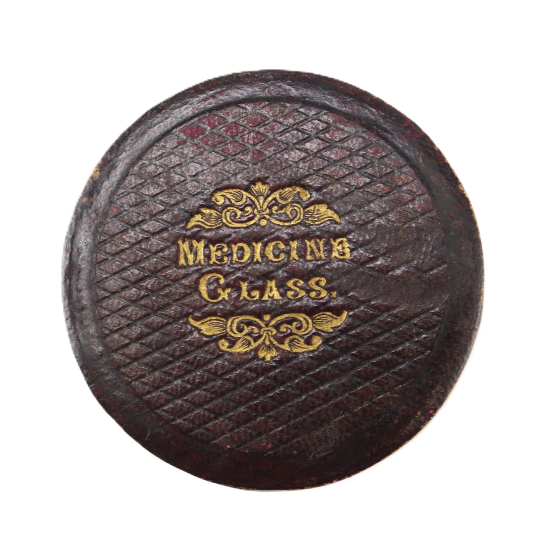 Oval, brown leather case lid with a diamond pattern and gold embossed text reading "MEDICINE GLASS.