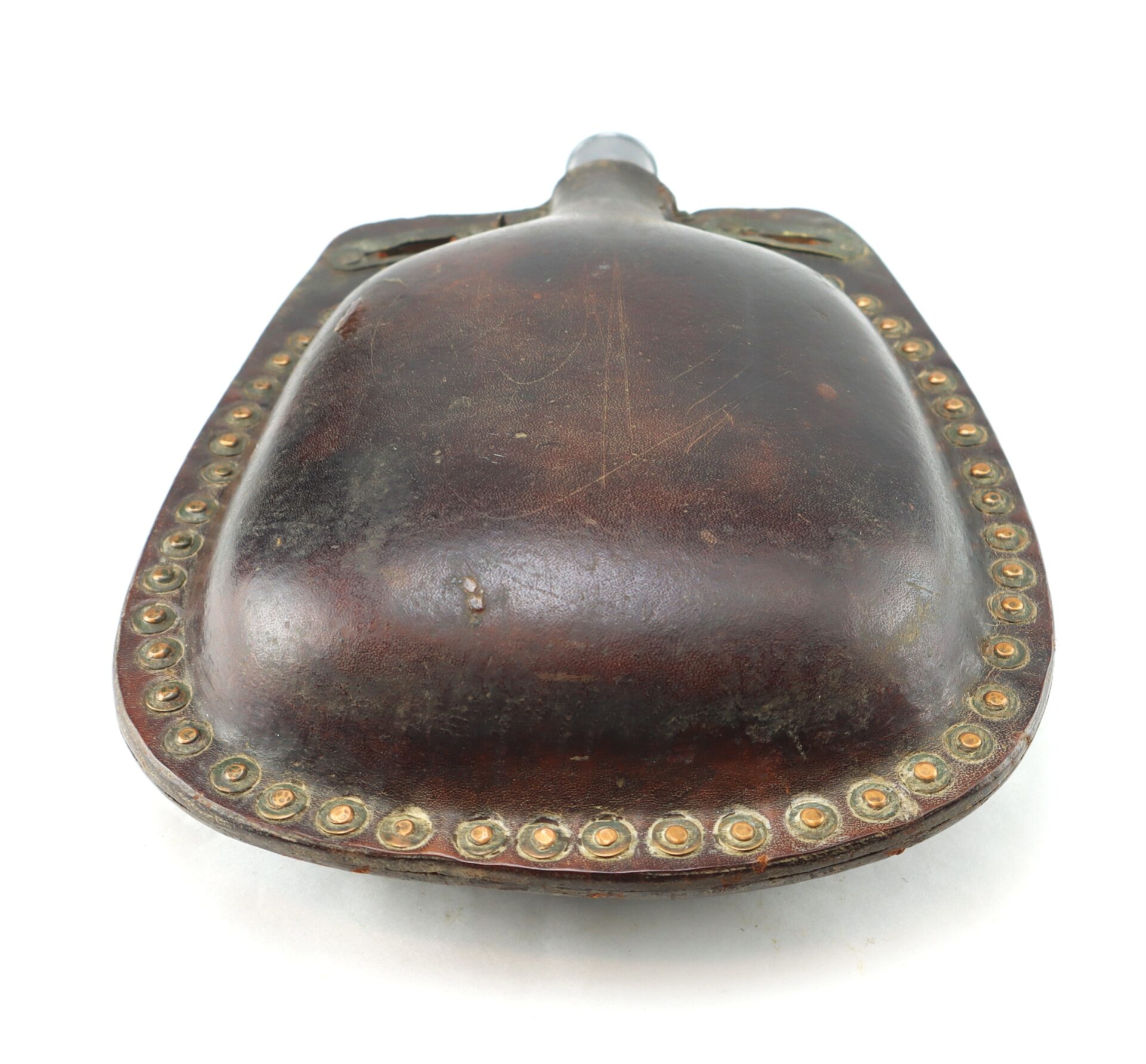 A vintage leather powder flask with a rounded body, metal spout, and brass stud detailing along the edge.