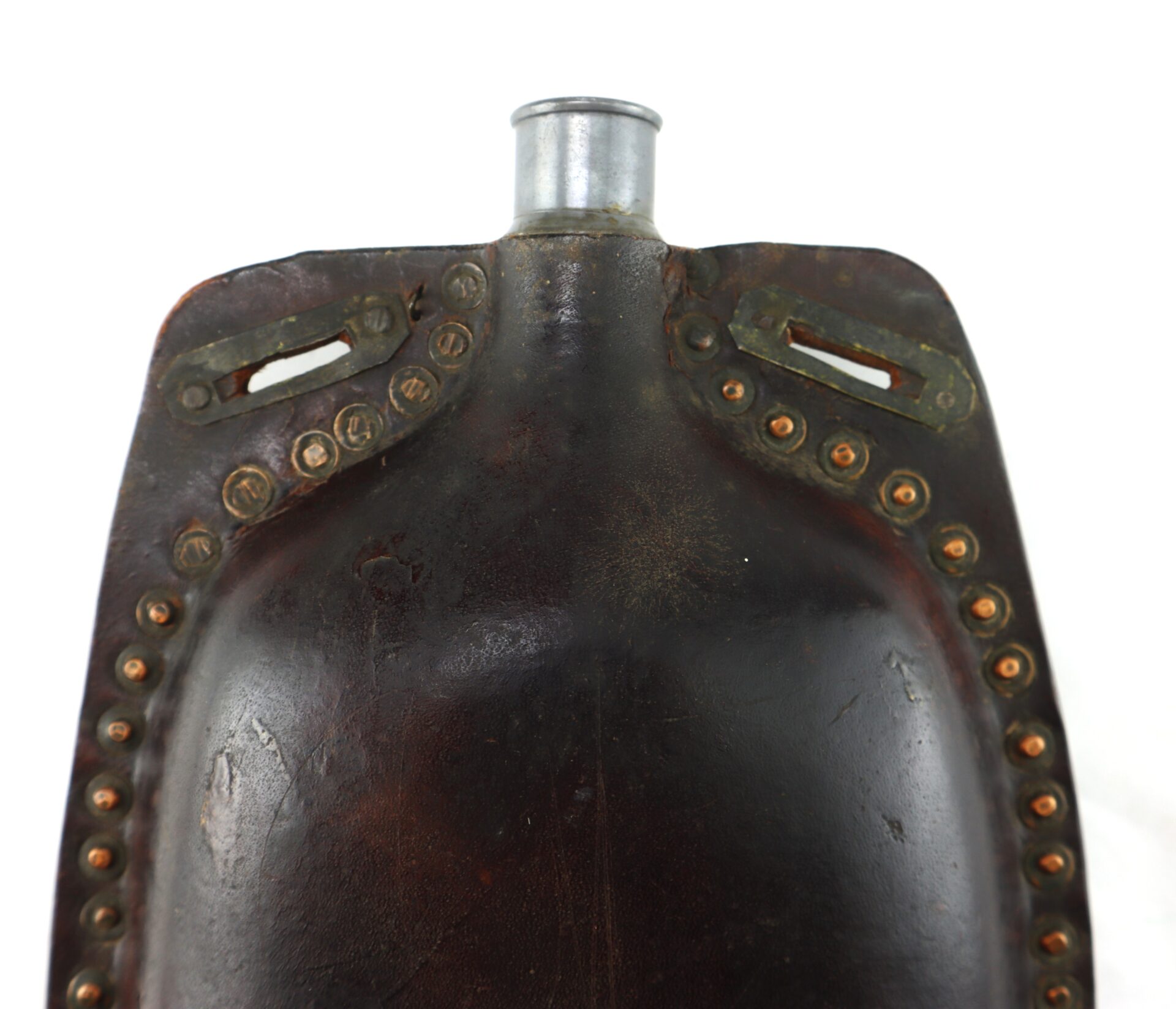 Close-up of a dark, vintage canteen with metal cap and riveted edges, showing signs of wear and two slots at the top for attaching straps.