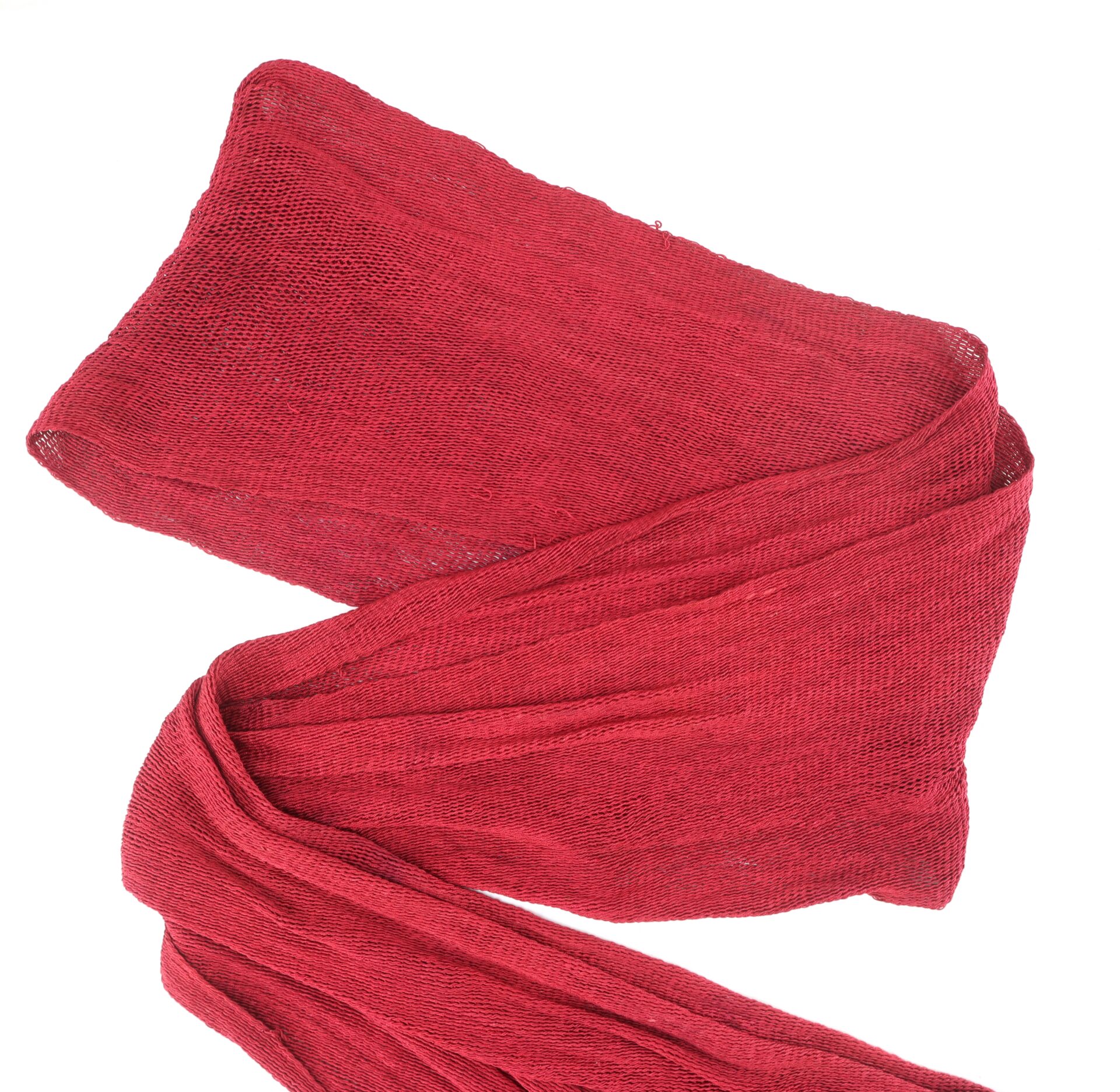A red, loosely woven scarf or piece of fabric is laid out on a white background.