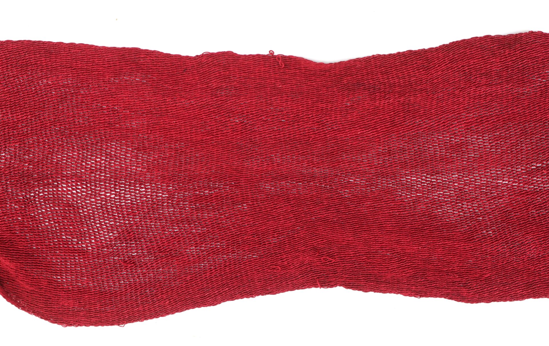 A piece of loosely woven red fabric with visible individual threads, displayed against a white background.