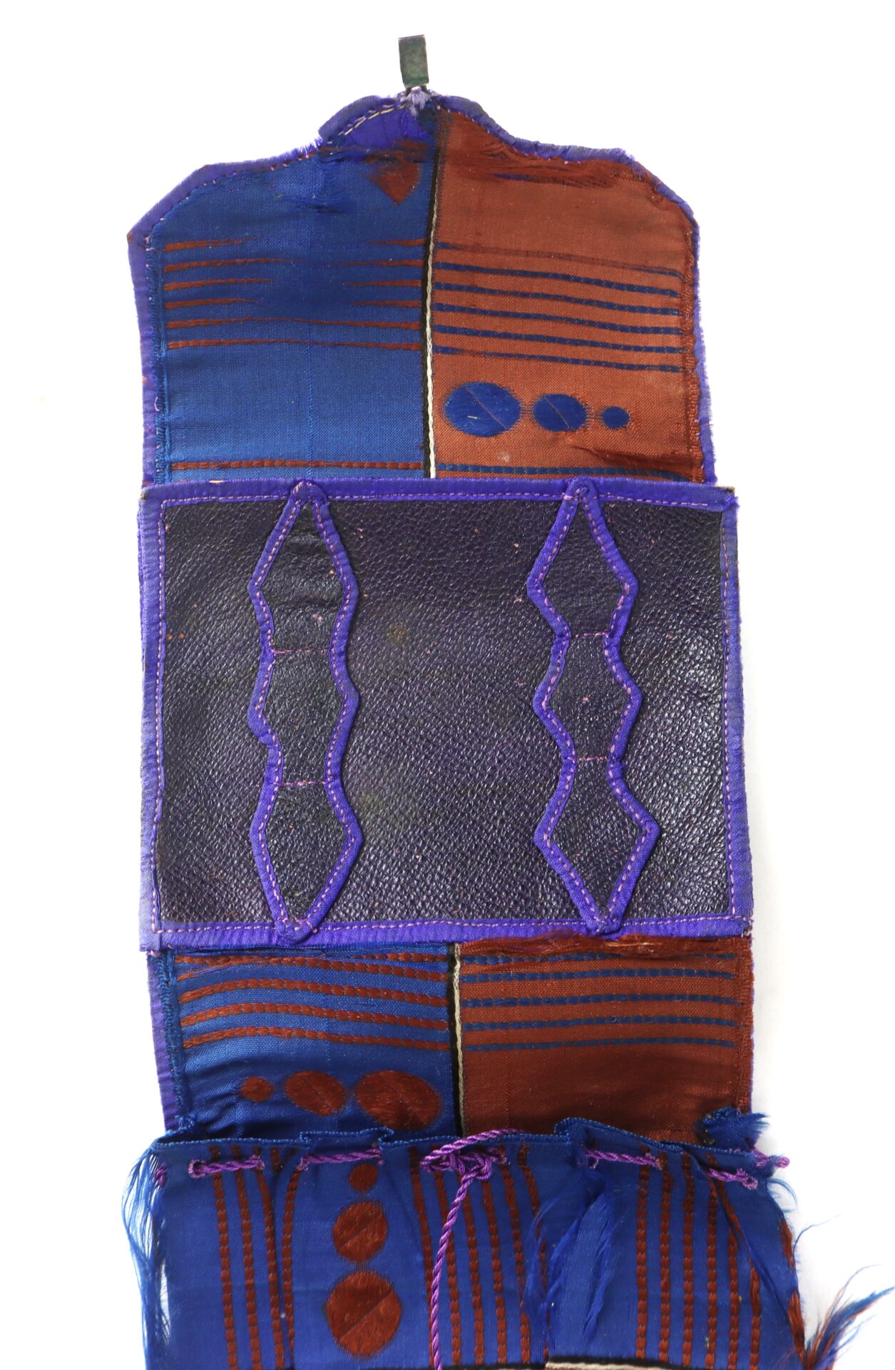 A rectangular textile pouch with blue, brown, and purple geometric patterns, featuring a central black panel bordered by purple trim.