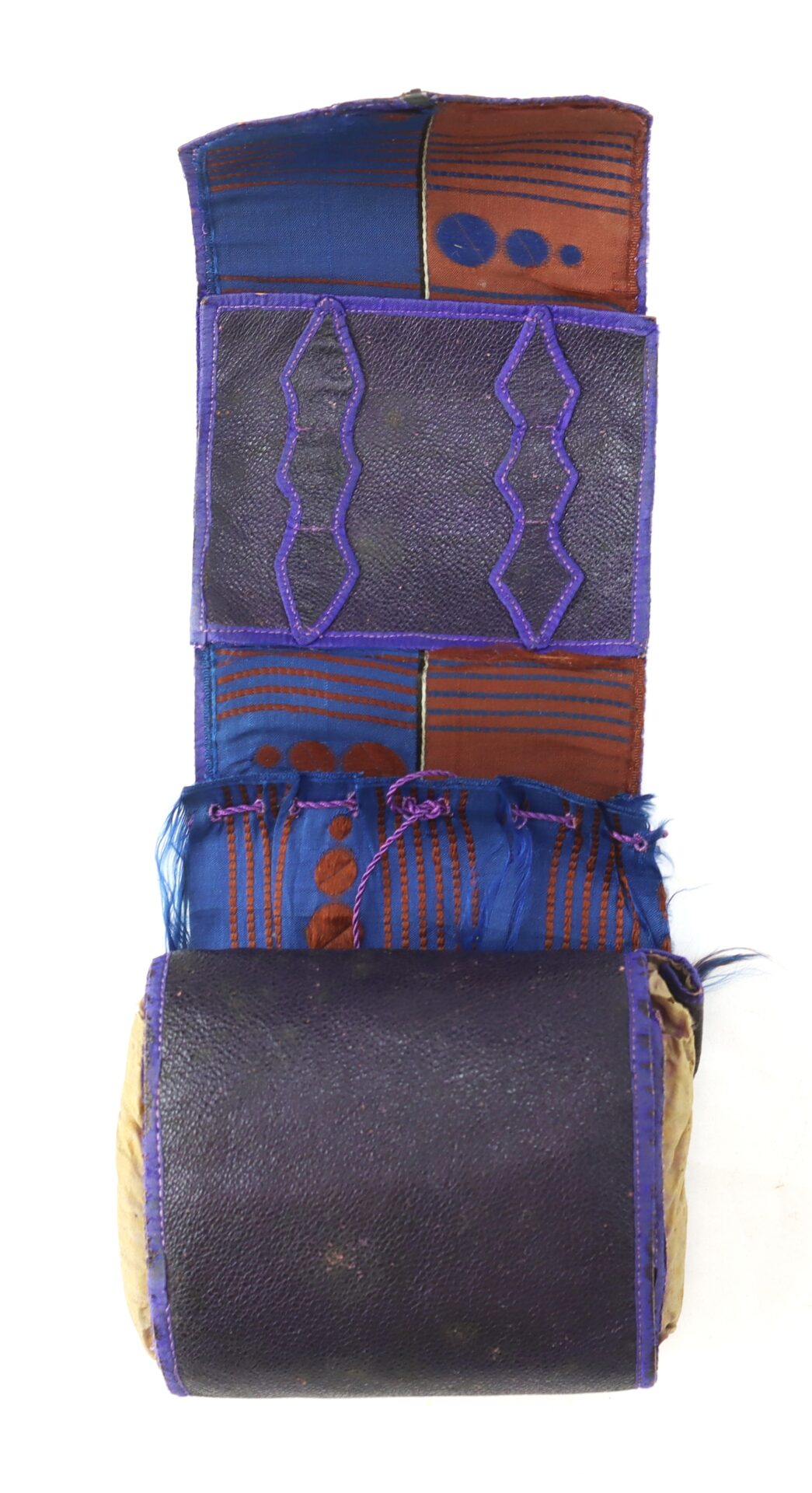 A fabric and leather headrest or pillow featuring blue, brown, and purple patterned sections with zigzag and dot designs.