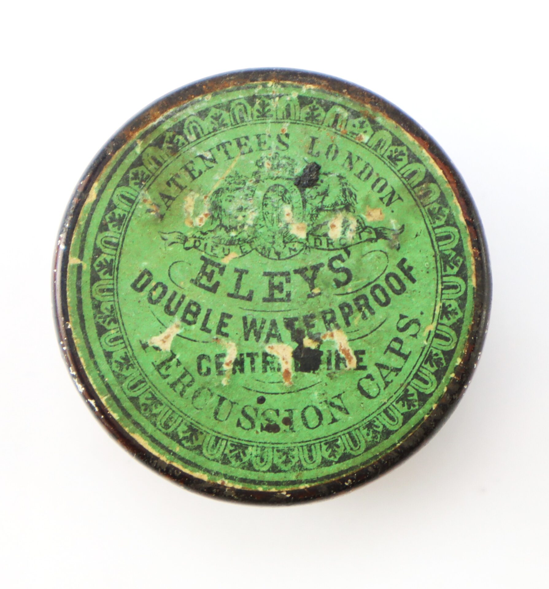 Round tin with a green label reading "Eley's Double Waterproof Percussion Caps, 1 Cent Each," featuring decorative text and designs, showing signs of wear and age.