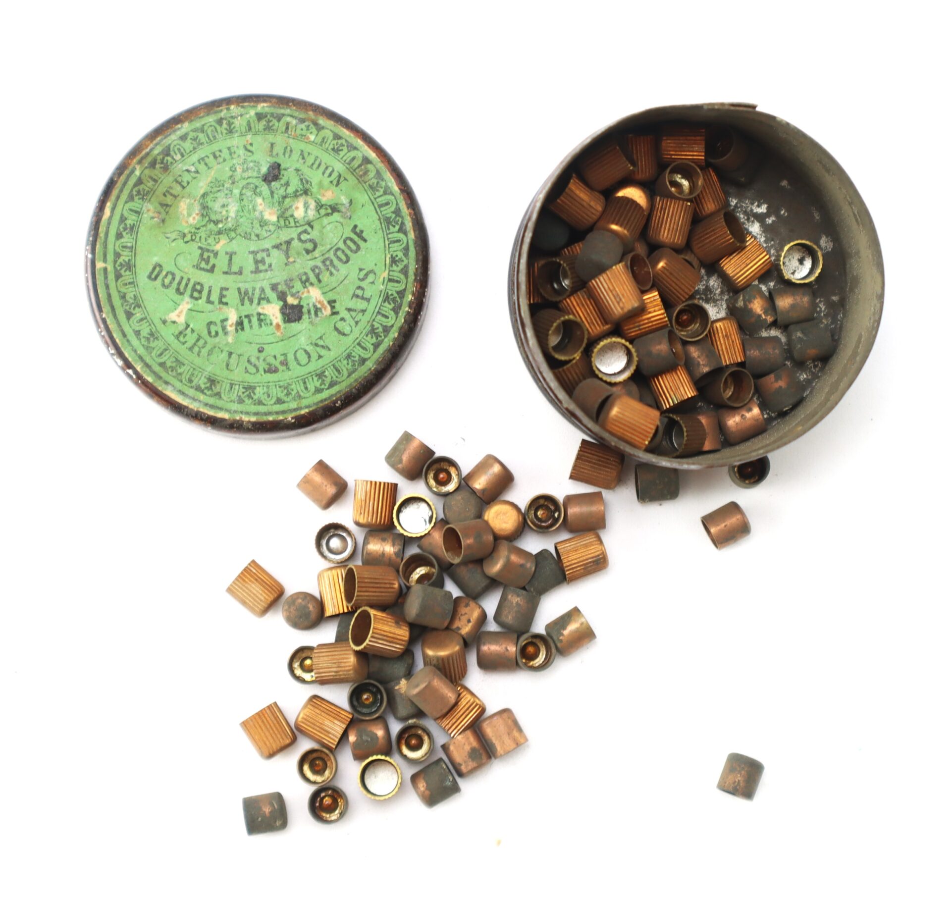 A round tin labeled "Eley’s Double Waterproof Central Fire Gun Caps" is open, with numerous copper percussion caps scattered around it.