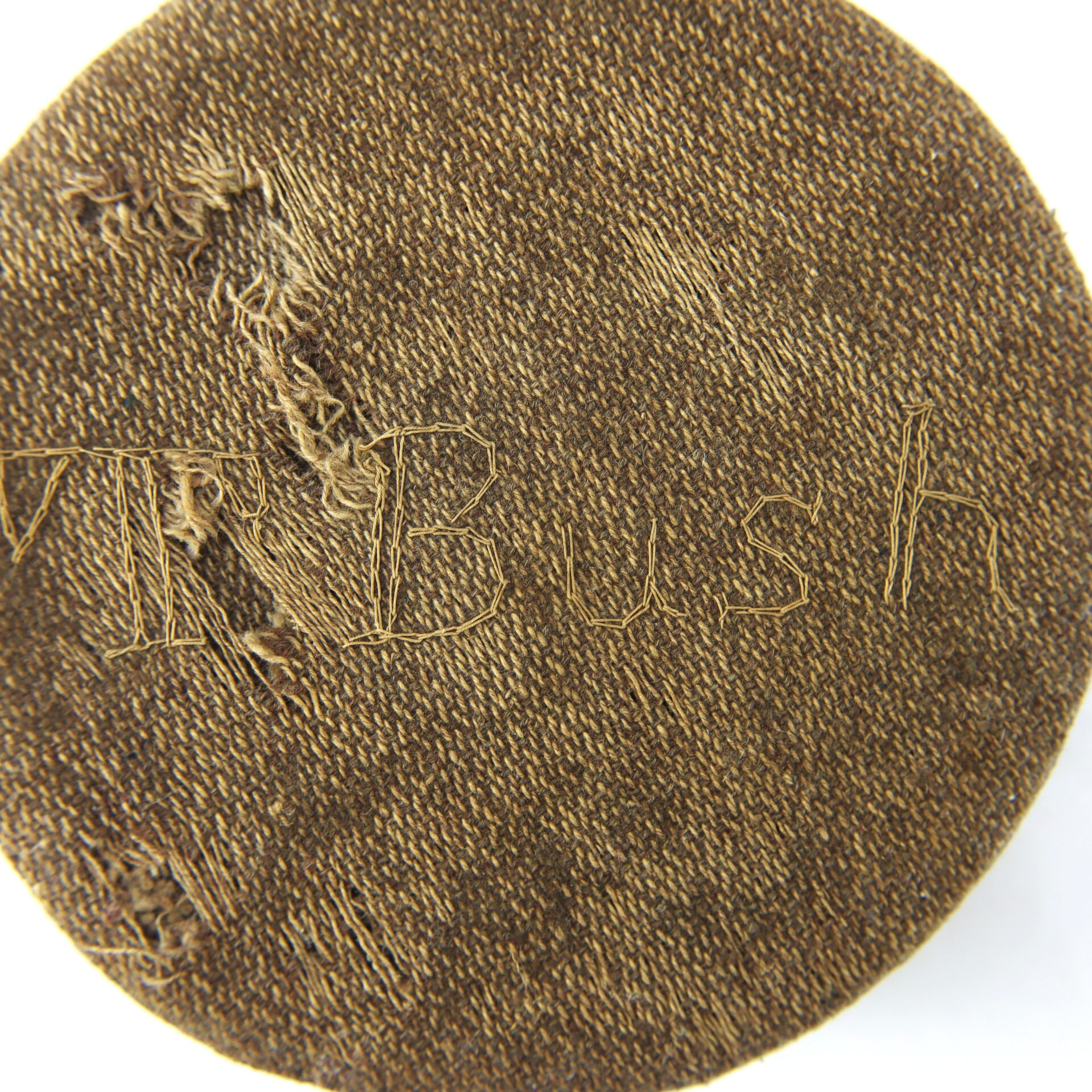 A brown fabric patch with the text "Mr Bush" roughly stitched into it with lighter threads.