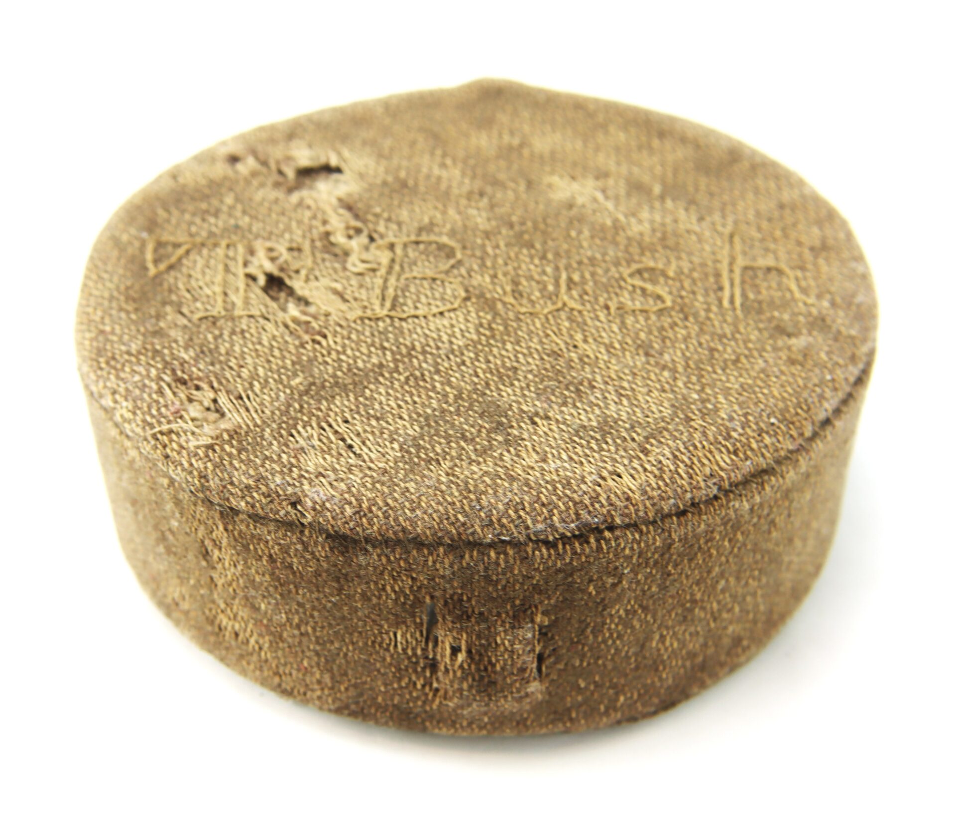 A round, textured, brown puck with worn edges and faint text, "Mr. Bush," engraved on the top surface.
