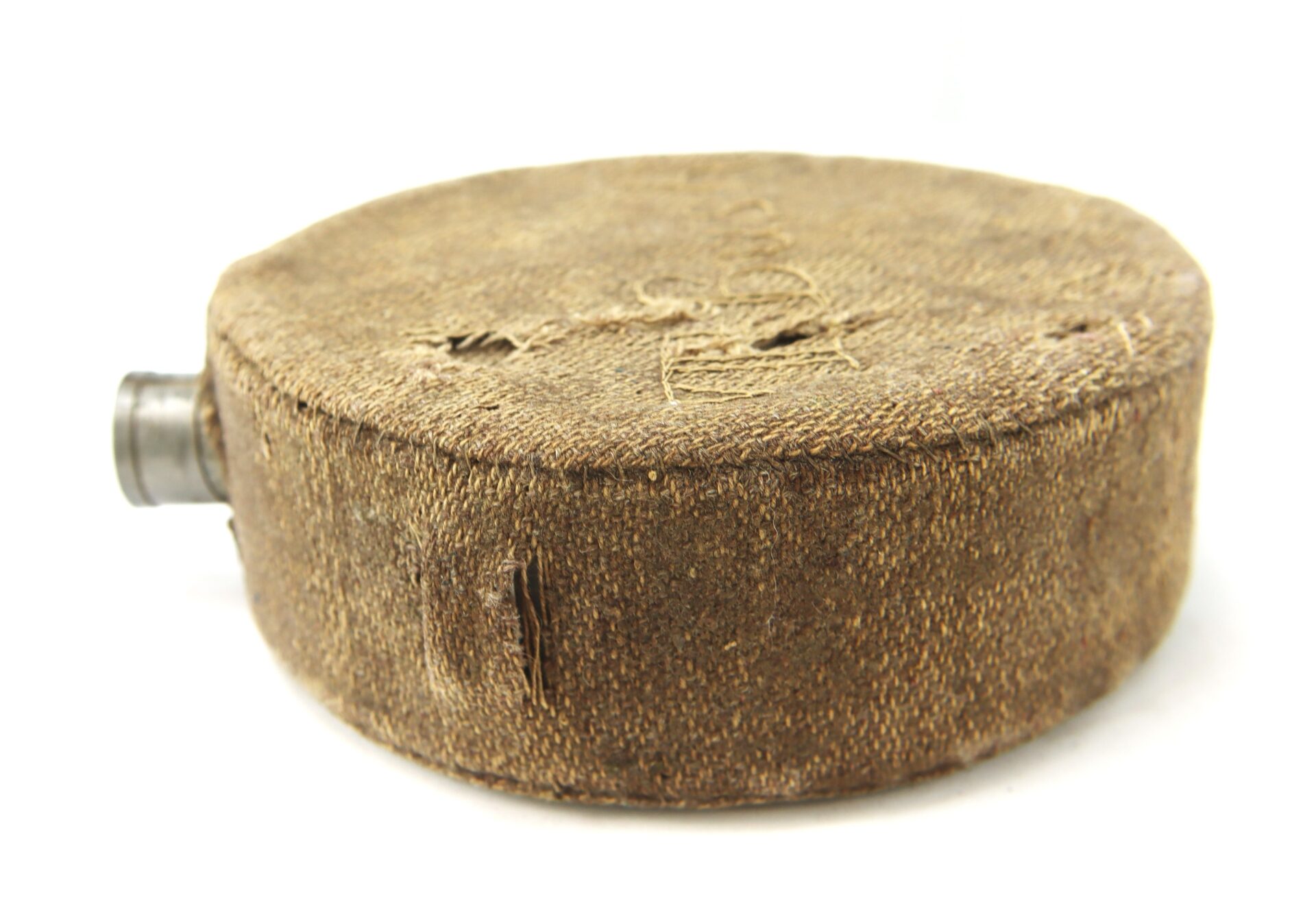A vintage round canteen covered in worn, brown fabric with a metal spout is shown lying on its side against a white background.