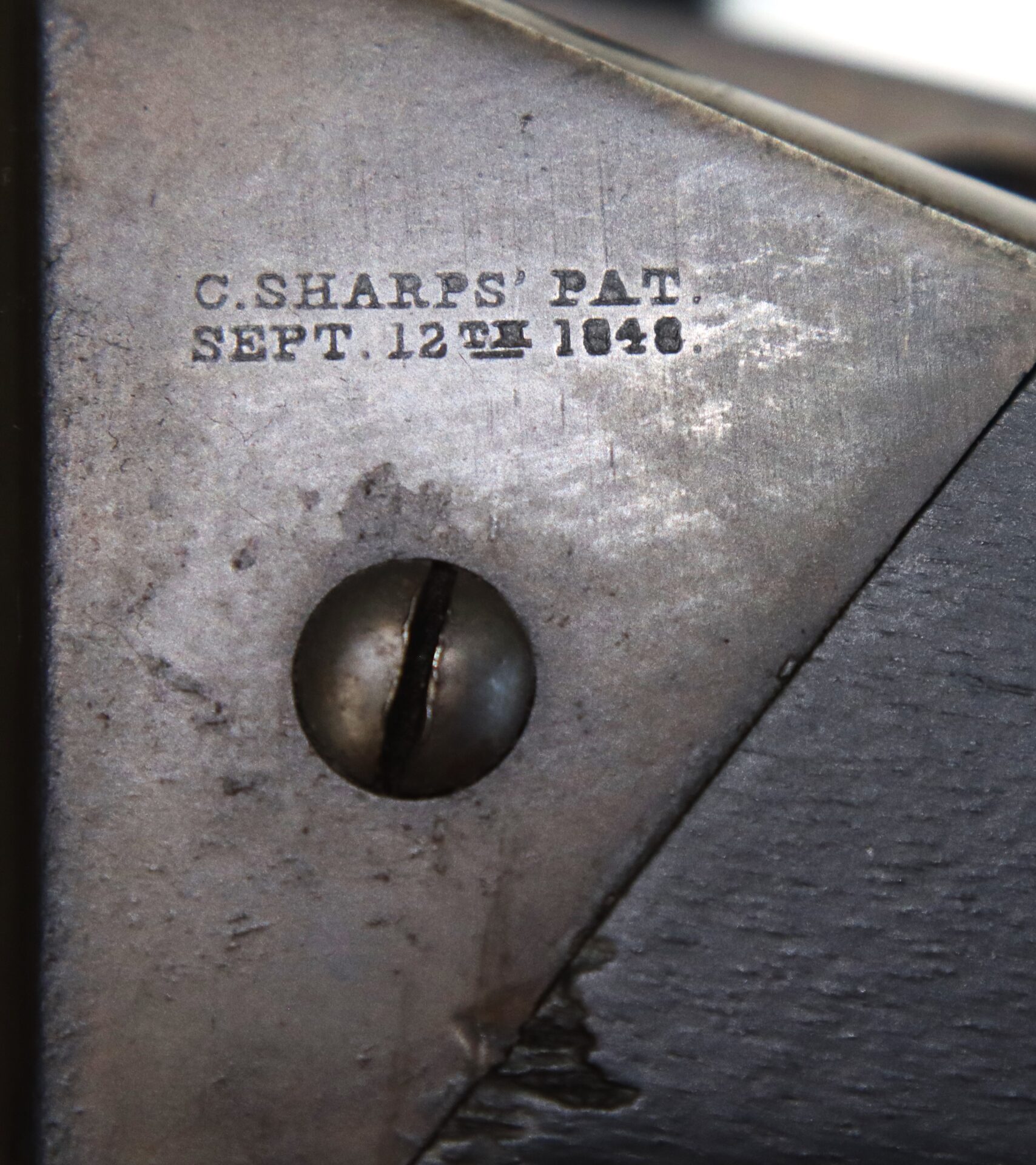 Close-up of a metal surface stamped with "C. SHARPS' PAT. SEPT. 12TH 1848" next to a slotted screw.