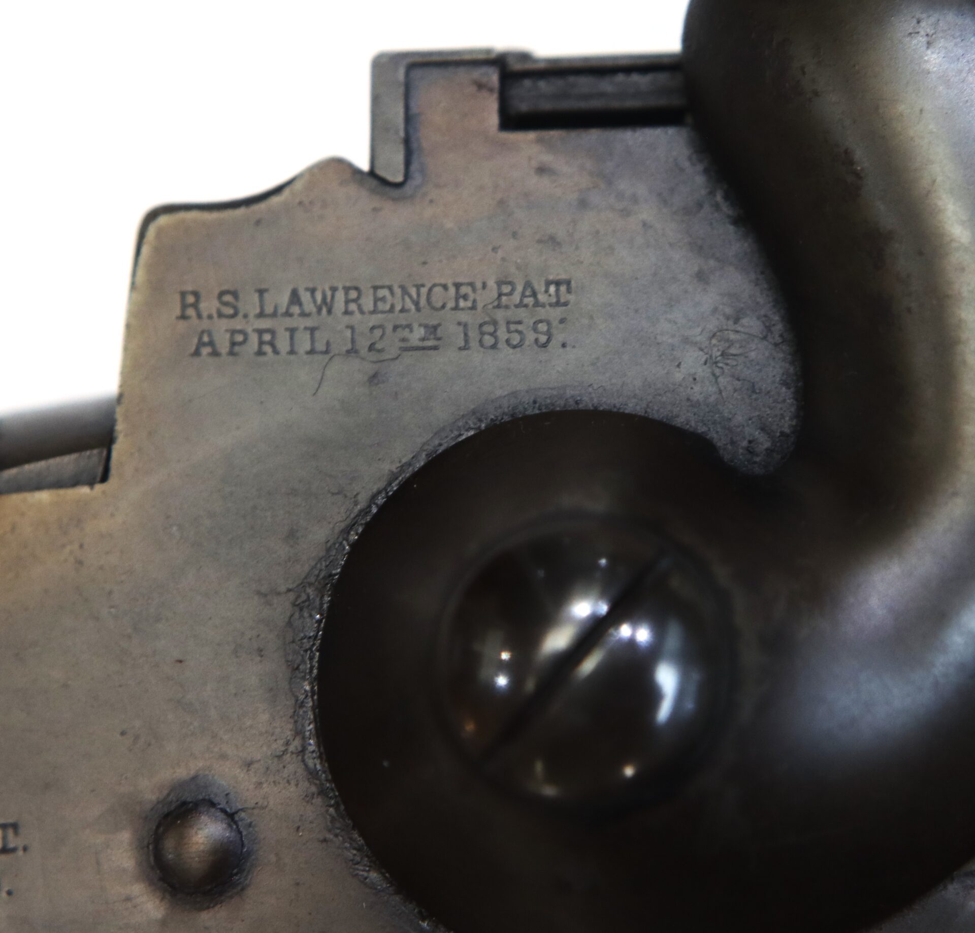 Close-up of a metal surface engraved with "R.S. LAWRENCE' PAT APRIL 12TH 1859" next to a large screw.
