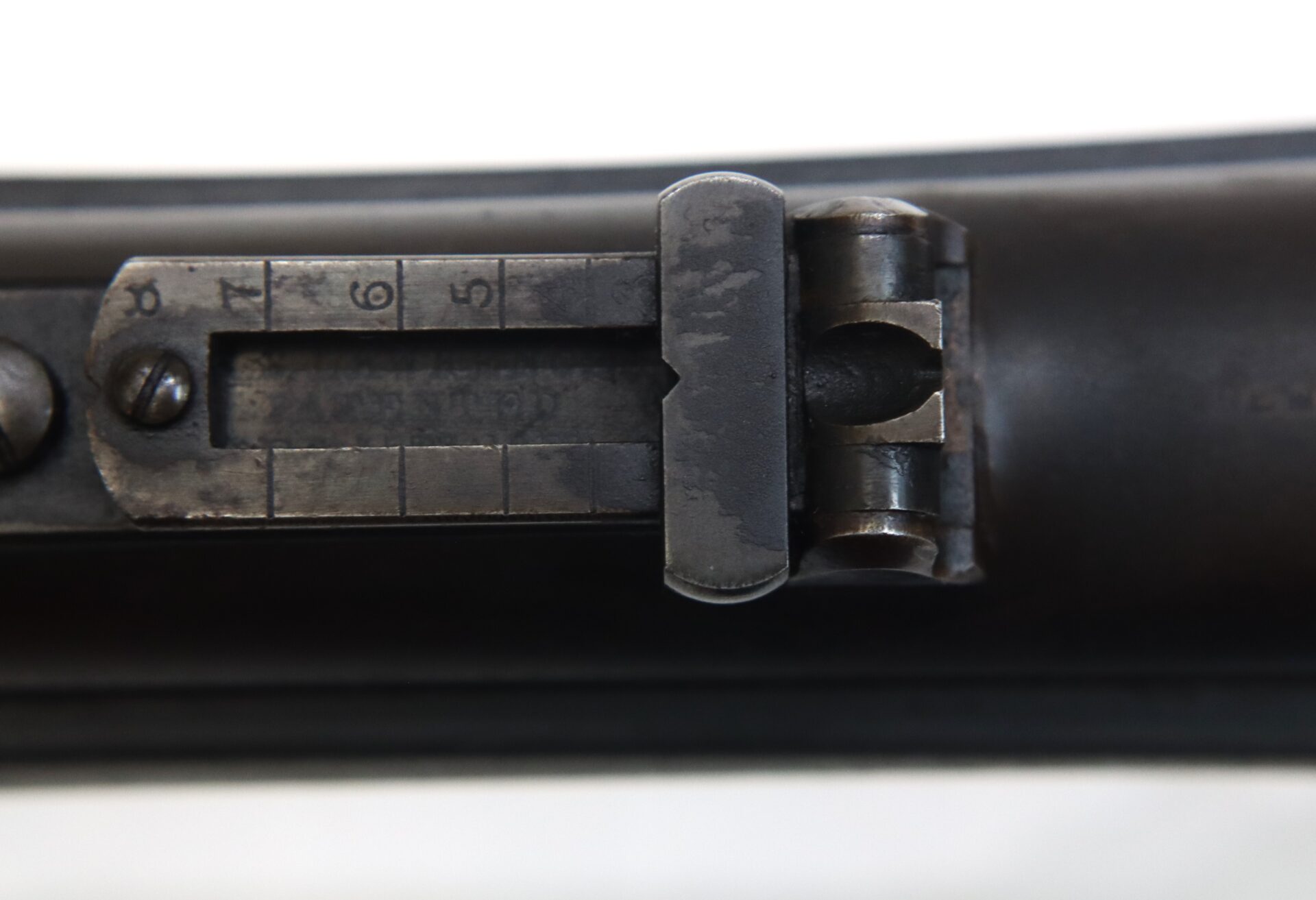 Close-up view of a metal rifle rear sight with numbered distance markings from 1 to 7.