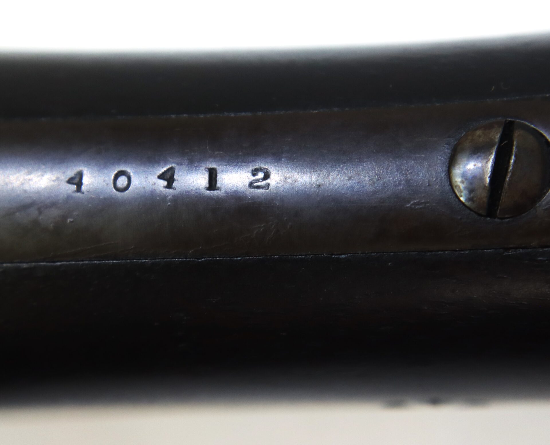 Close-up of a metal surface with the engraved number "40412" next to a flathead screw.
