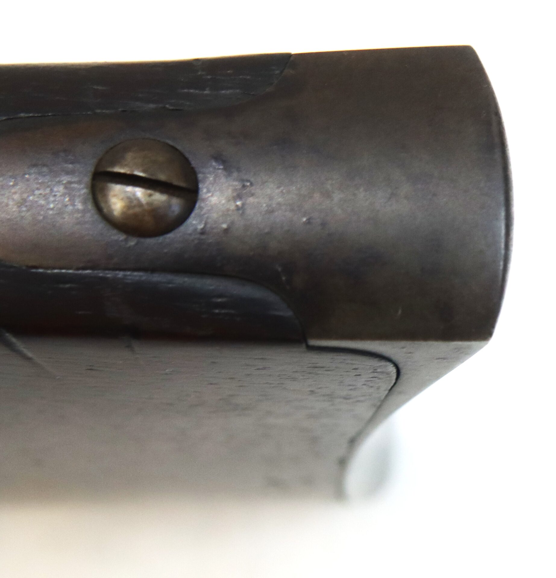 Close-up of a metal hinge or joint with a slotted screw, attached to a dark wooden surface, against a white background.