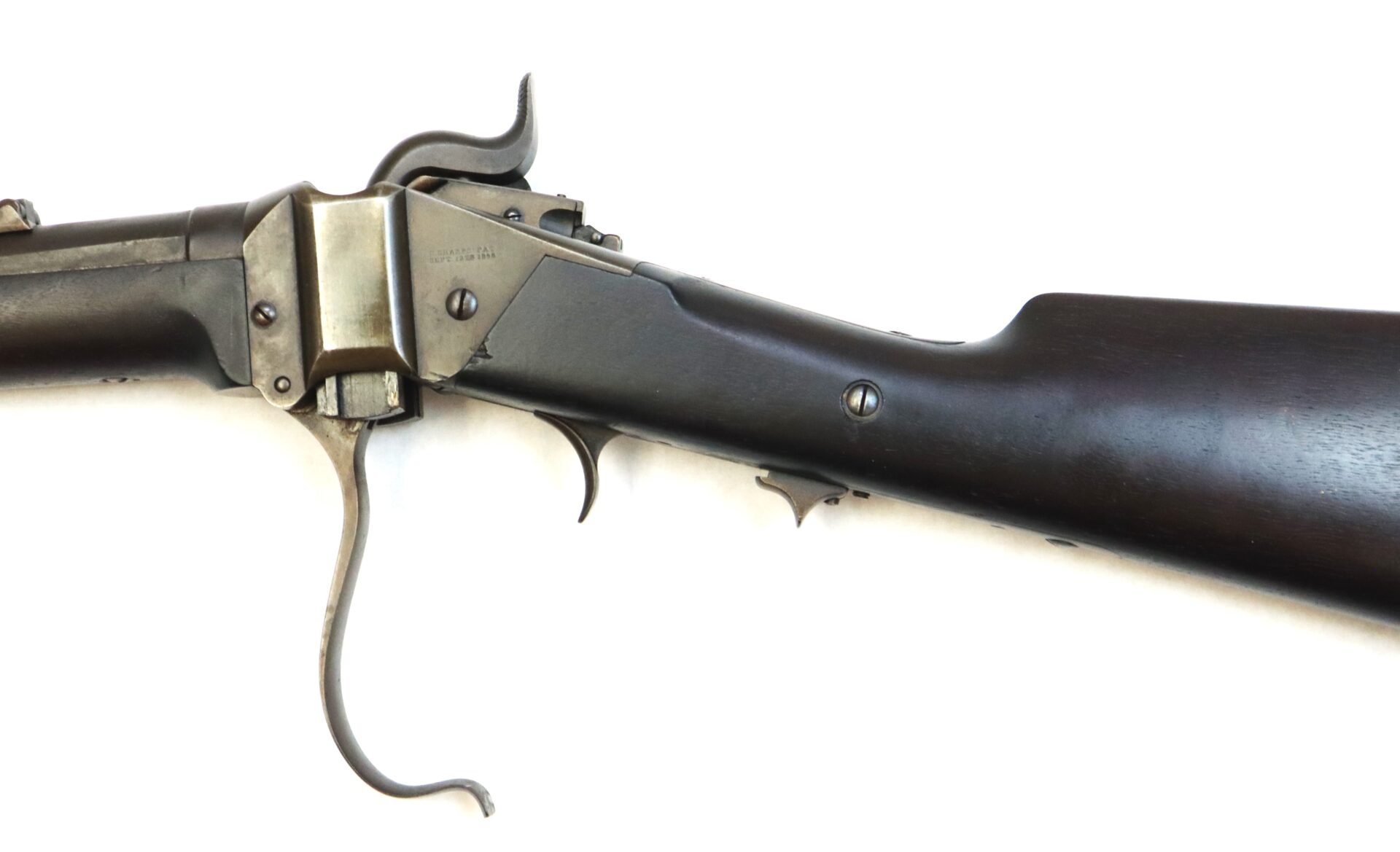 Close-up view of an antique lever-action rifle with a dark wooden stock and metal receiver, photographed against a white background.