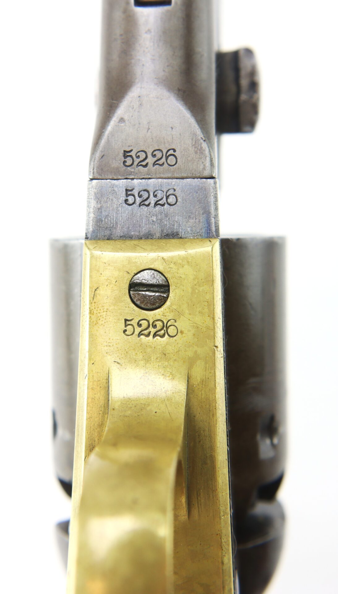 Close-up view of a revolver showing the serial number 5226 stamped on both the brass and steel parts of the firearm.