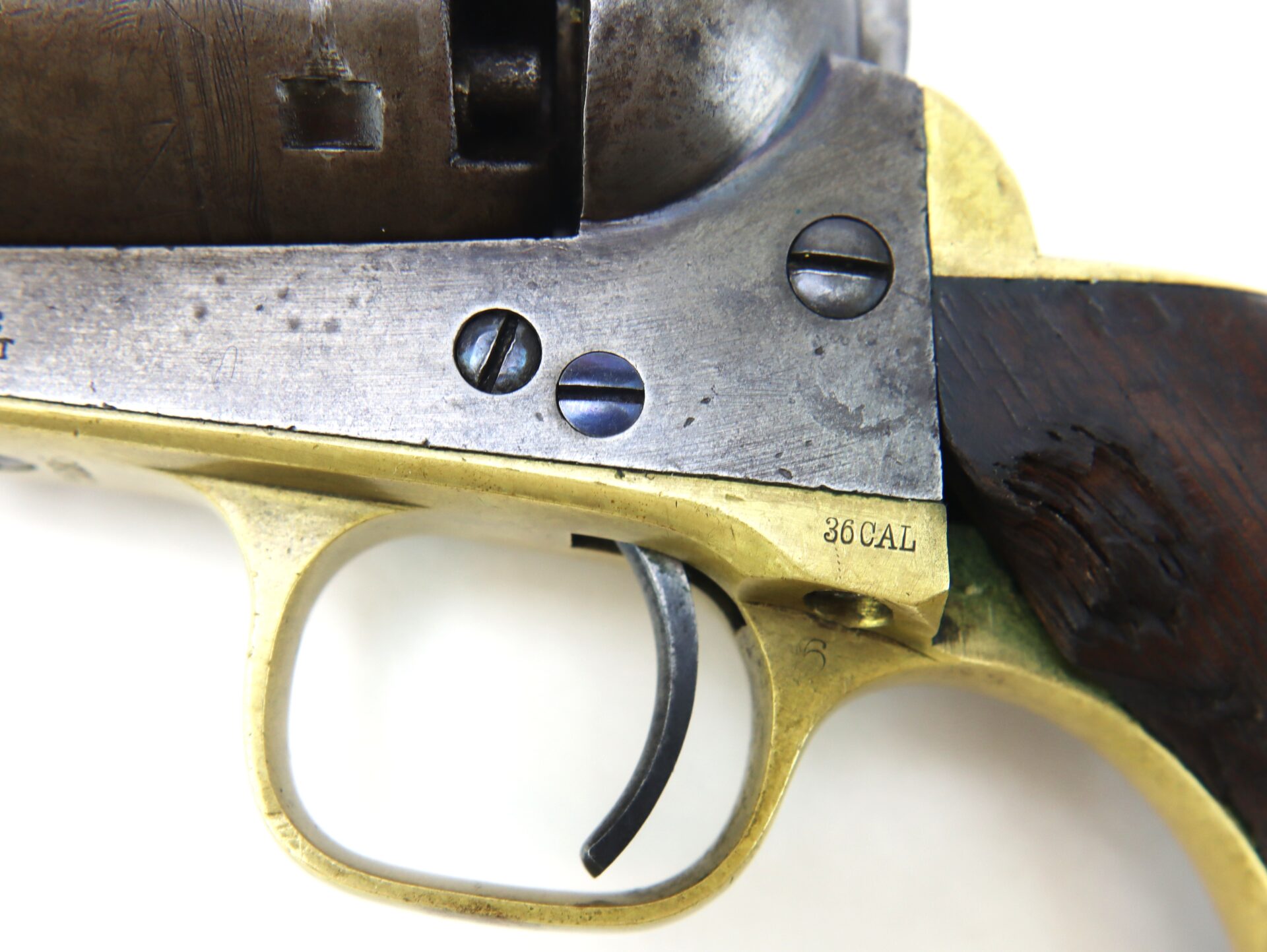 Close-up of a revolver with a brass frame, visible trigger, wooden grip, and “36 CAL” stamped on the metal.
