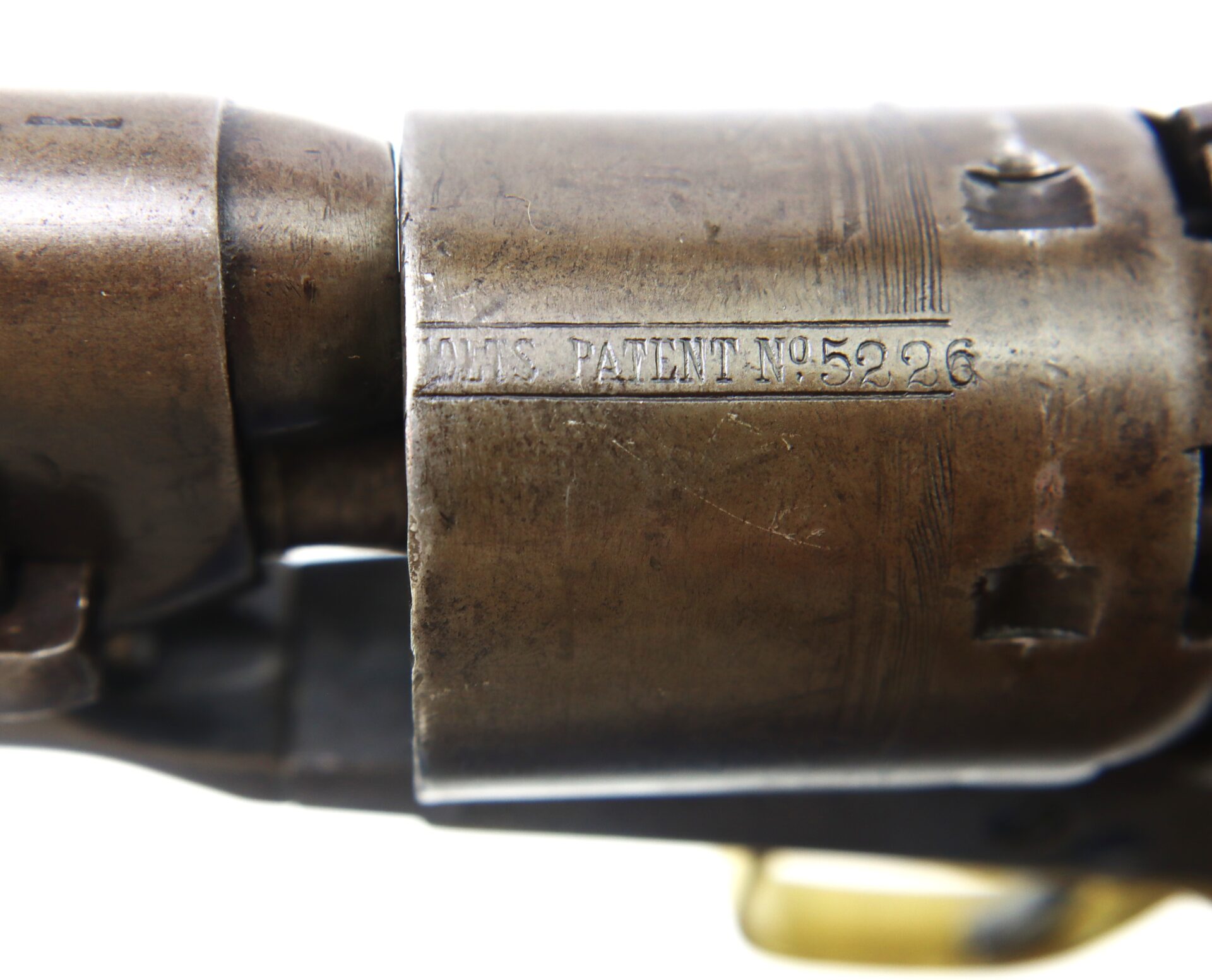 Close-up view of a metal firearm cylinder engraved with the text "COLTS PATENT N°5236.